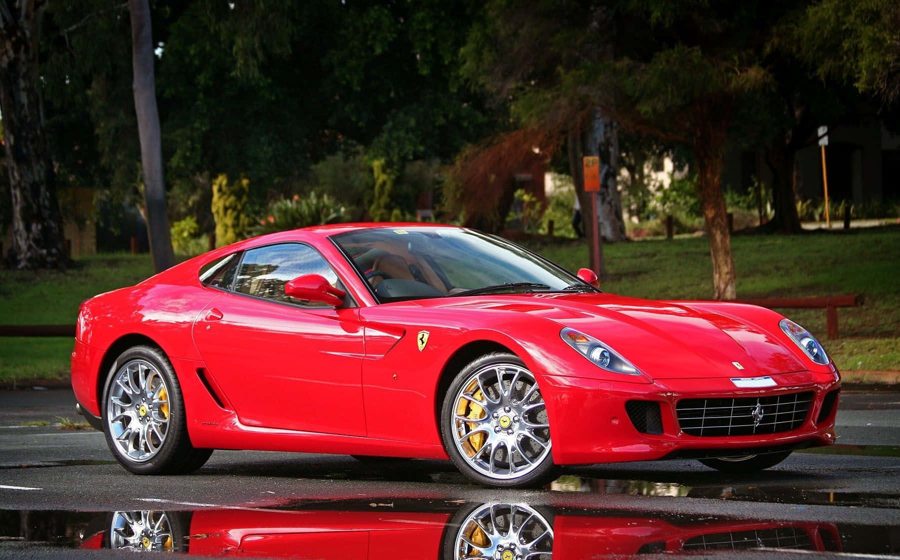 Ferrari 599 Gtb Fiorano 桌布 壁紙 — 一輛光亮的紅色法拉利跑車在濕漉漉的路面上閃耀，斑駁的陽光下映出完美倒影。