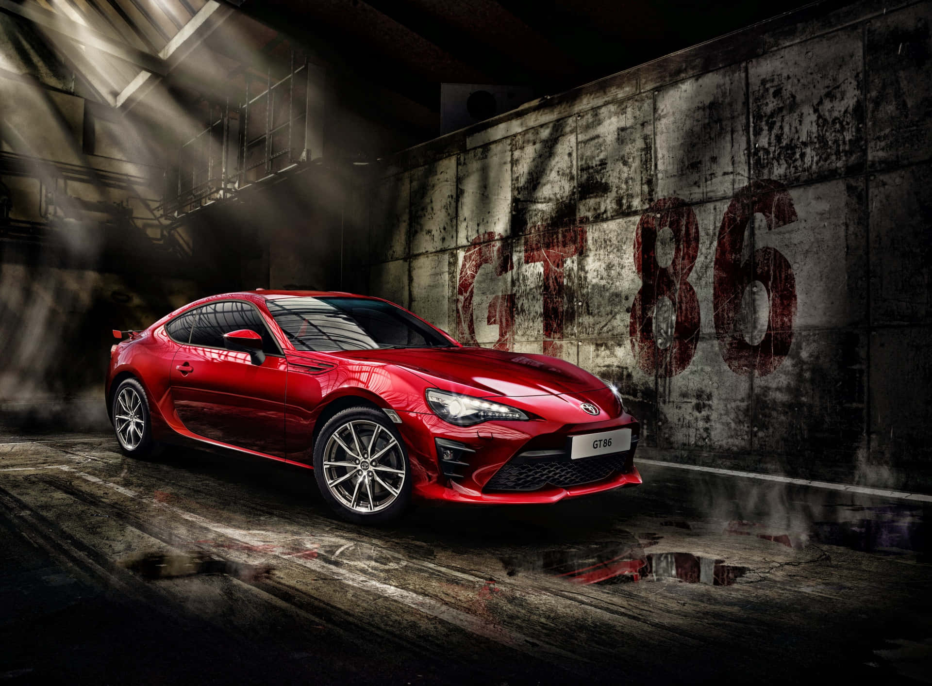 昏暗工業車庫中的紅色跑車，帶有塗鴉和聚光燈。 — Toyota Supra Mk4 壁紙