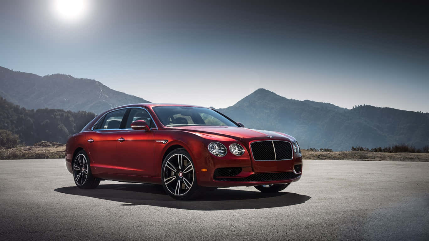 1366x768 Bentley 桌布 壁紙 — 一輛光亮的紅色賓利轎車停放在陽光普照的瀝青路上，背景是山區地形。