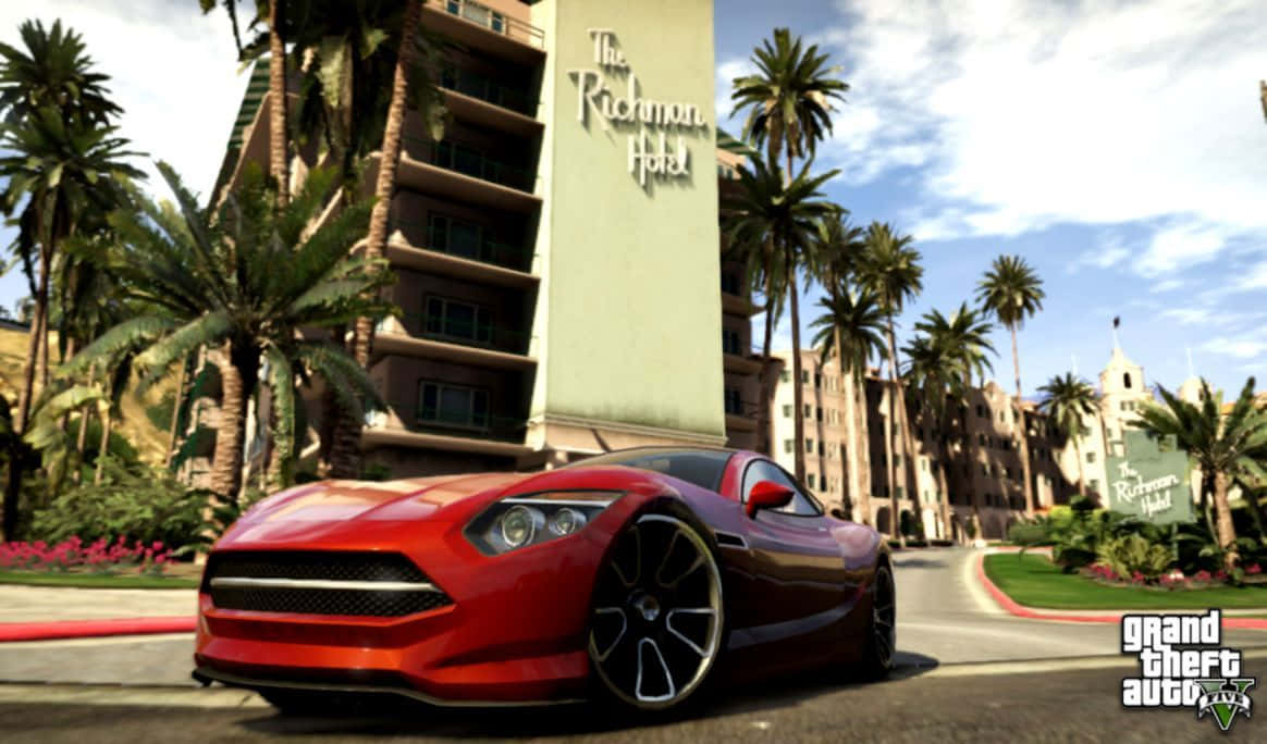 Gta 5 Desktop 桌布 壁紙 — 一輛光亮的紅色跑車停泊在陽光明媚的街道上，兩旁種有棕櫚樹和里士滿酒店，處於電子遊戲場景中。