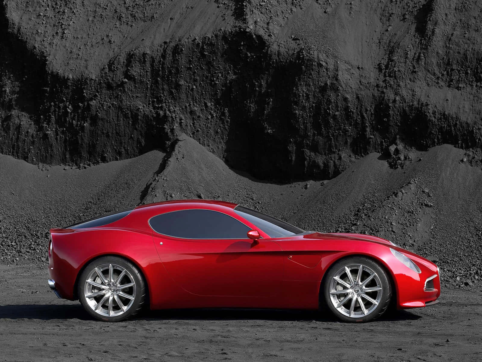 Alfa Romeo 8c Competizione 桌布 壁紙 — 一輛光亮的紅色跑車在明亮的日光下，在黑色火山岩背景下閃閃發光。