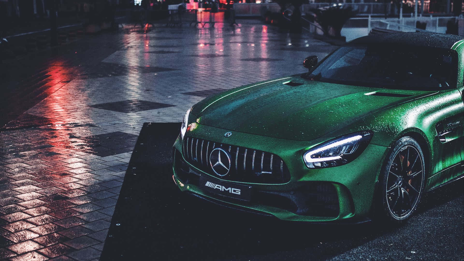 主題 桌布 壁紙 — 一輛光亮的綠色Mercedes-AMG跑車在夜晚濕潤的城市街道上，在霓虹燈下閃閃發光。