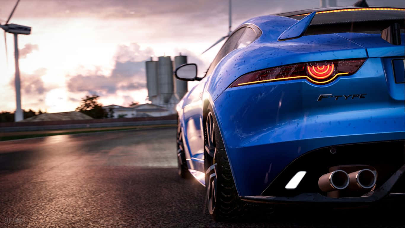 1366x768 Project Cars 桌布 壁紙 — 一輛光亮的藍色積架F-Type跑車在日落時分在濕滑的道路上行駛，背景有風力渦輪機和筒倉。