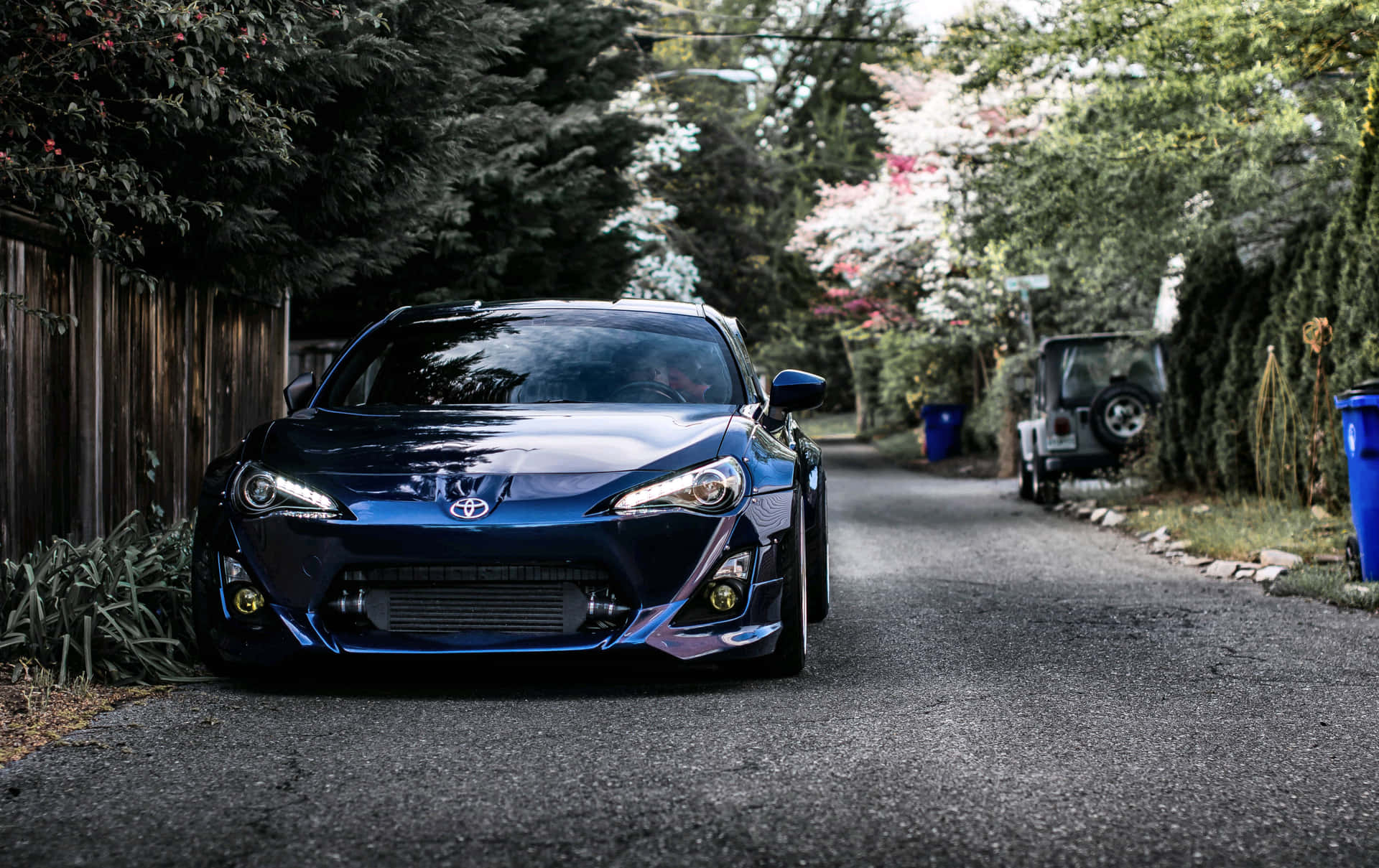 藍色跑車停泊在寧靜的住宅街道上，兩旁有樹木和秋葉。 — Toyota Supra Mk4 壁紙
