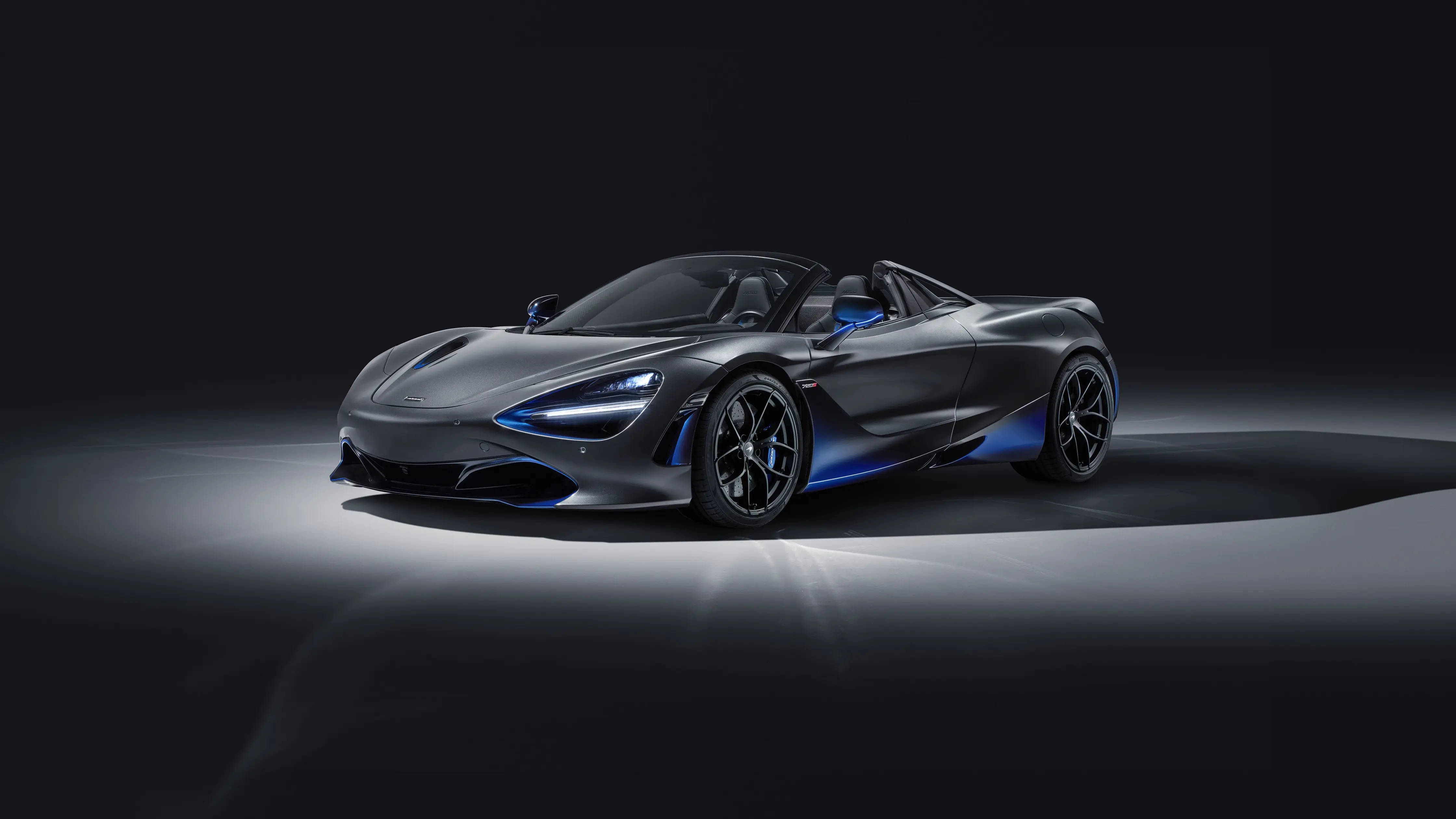 跑車 桌布 壁紙 — 一輛光滑的啞光灰色McLaren 720S Spider，帶有發光的藍色點綴和車頭燈，在黑暗的攝影棚背景下照亮。