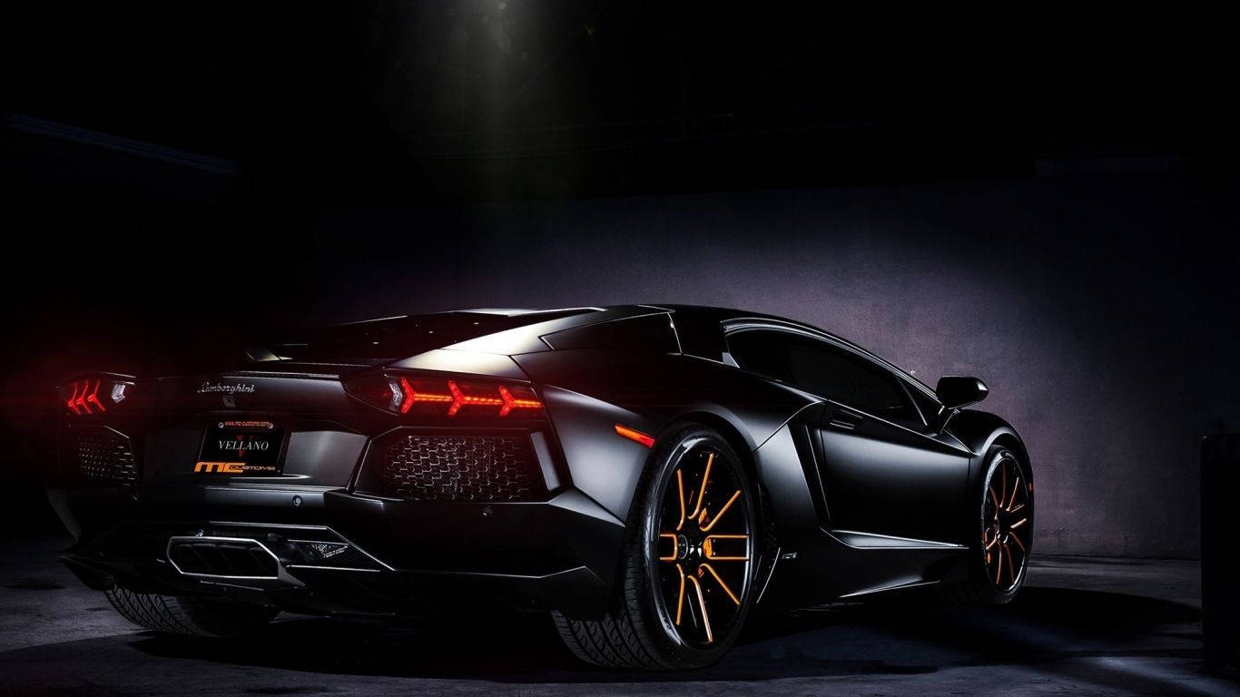 跑車 桌布 壁紙 — 一輛光滑的消光黑色藍寶堅尼Aventador，帶有發光的橙色飾邊和紅色尾燈，在黑暗的車庫中戲劇性地照亮。