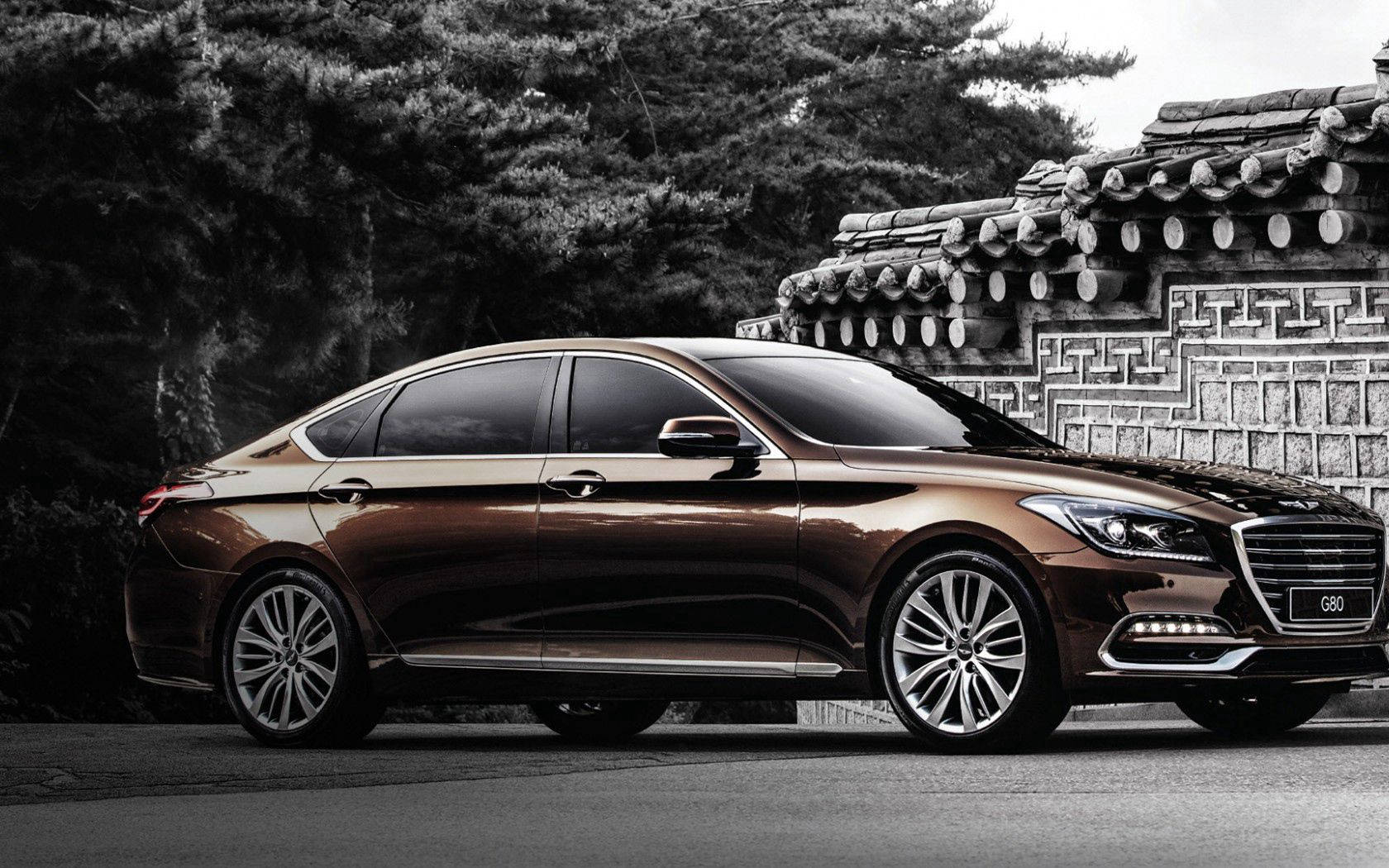 Hyundai 桌布 壁紙 — 一輛光滑的青銅色轎車停在傳統韓式瓷磚牆旁，背景為單色調的深色樹木。