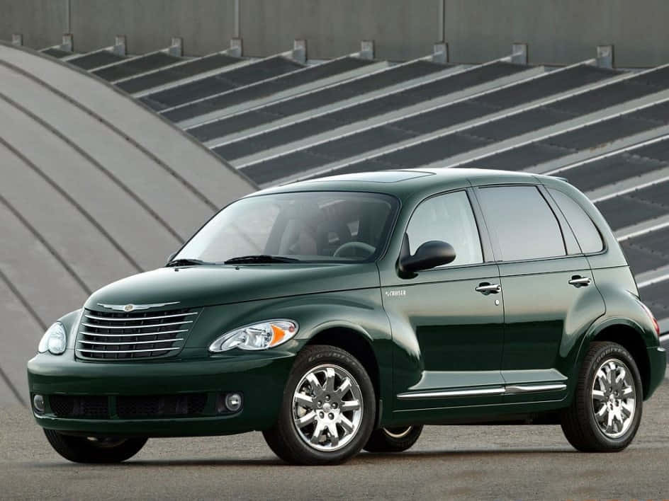 Chrysler Pt Cruiser 桌布 壁紙 — 一輛光澤深綠色的克萊斯勒 PT Cruiser 停在一個現代混凝土體育場前，設有分層座位。
