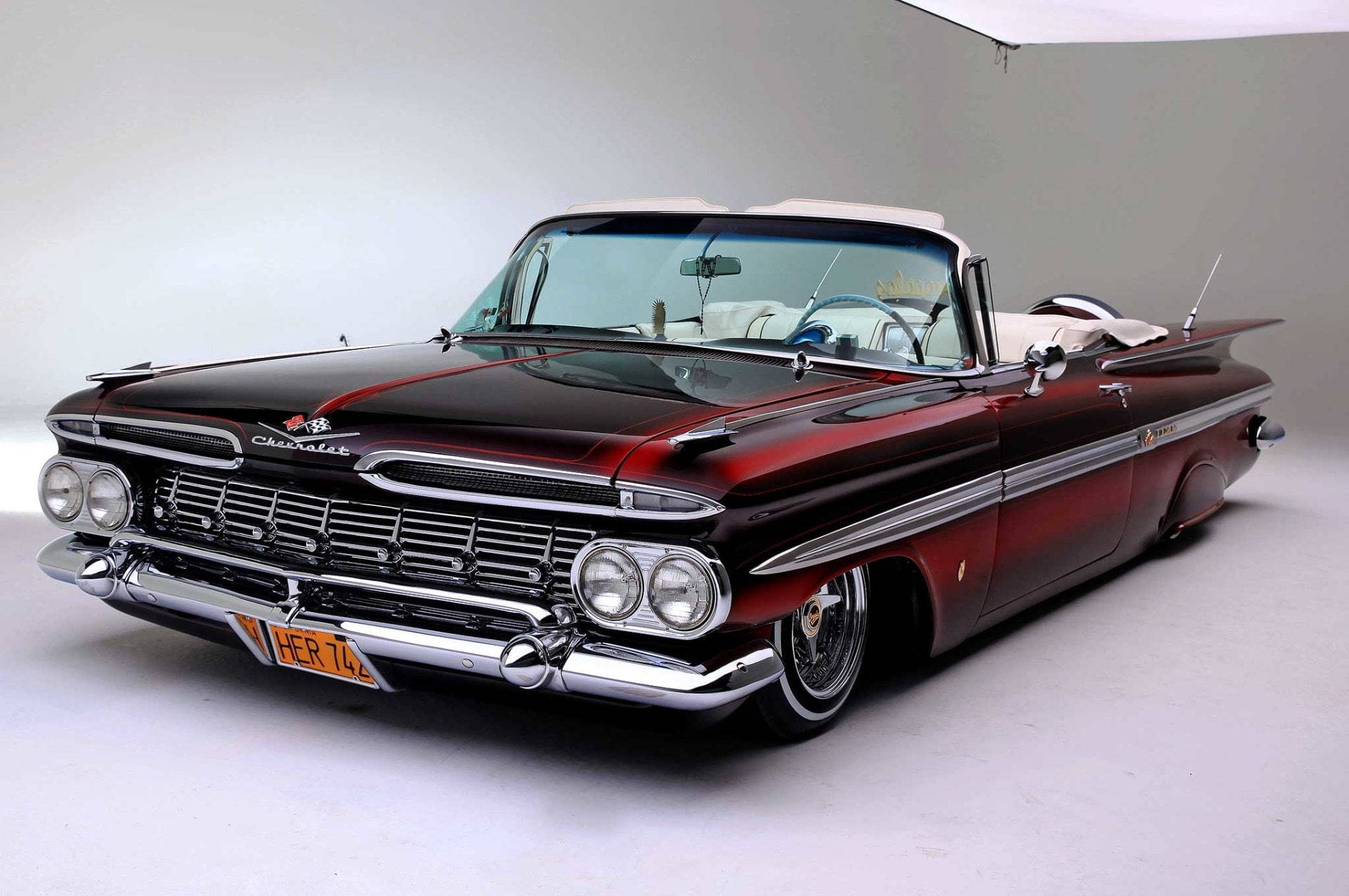 Lowrider 桌布 壁紙 — 一輛光澤的栗色1959年雪佛蘭敞篷車，帶有鍍鉻裝飾和白色車頂，在極簡的攝影棚環境中擺拍。