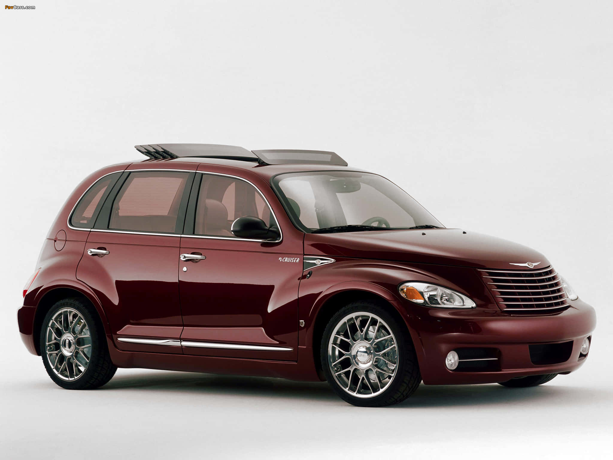 Chrysler Pt Cruiser 桌布 壁紙 — 一輛光澤的栗色PT Cruiser，配備鍍鉻輪圈和車頂行李架，在純白的工作室背景前蓄勢待發。