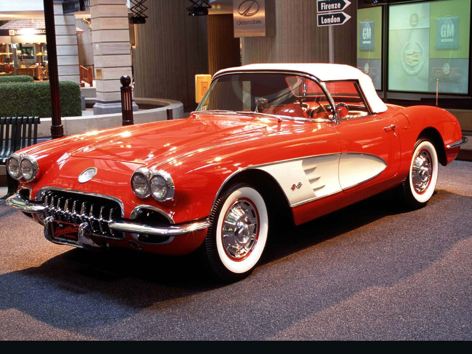 classic 桌布 壁紙 — 一輛光澤的紅白經典Corvette敞篷車在博物館般的室內燈光下閃閃發光。
