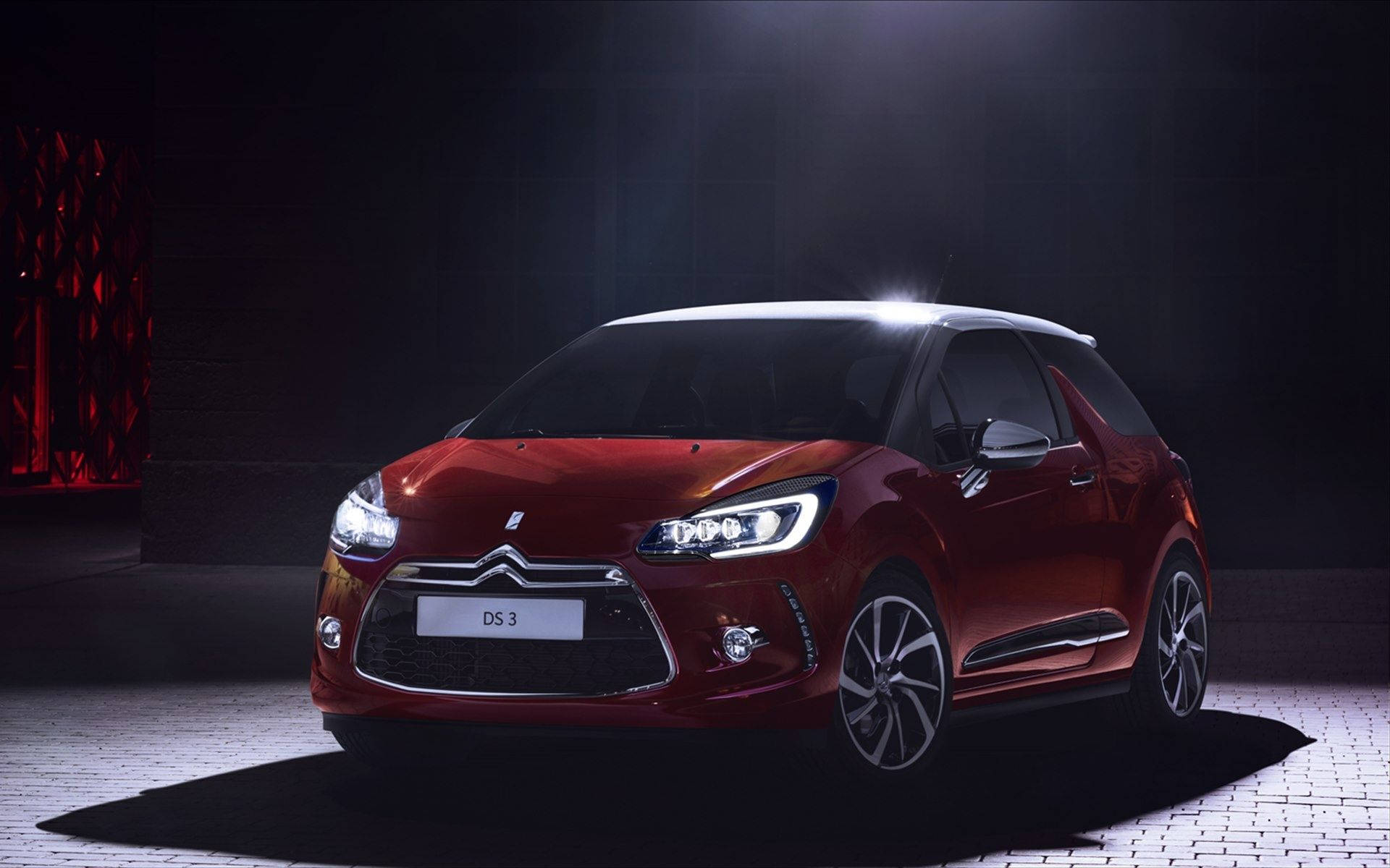 Citroen 桌布 壁紙 — 一輛光澤的紅色 DS 3 汽車在黑暗的攝影棚中，被聚光燈和瓷磚地板戲劇性地照亮。