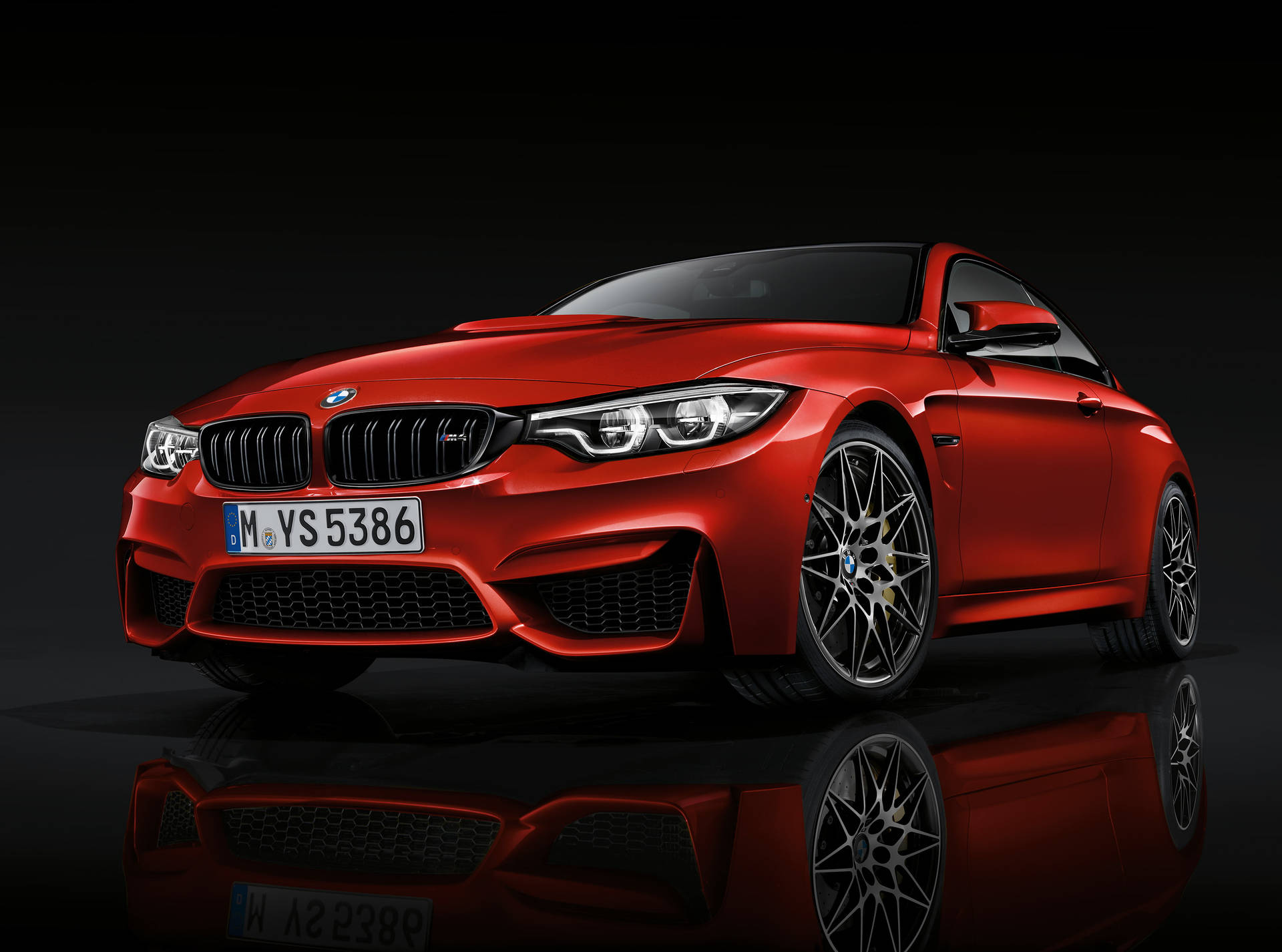 紅色BMW M4跑車在黑色表面上反射，攝影棚燈光。