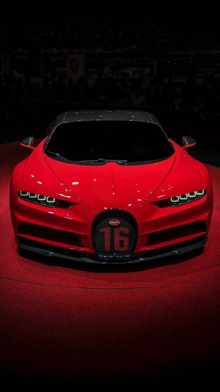 Best Bugatti 桌布 壁紙 — 一輛光澤的紅色Bugatti Chiron Super Sport 16，帶有'16'格柵徽章，在車展的紅地毯上於聚光燈下閃耀。