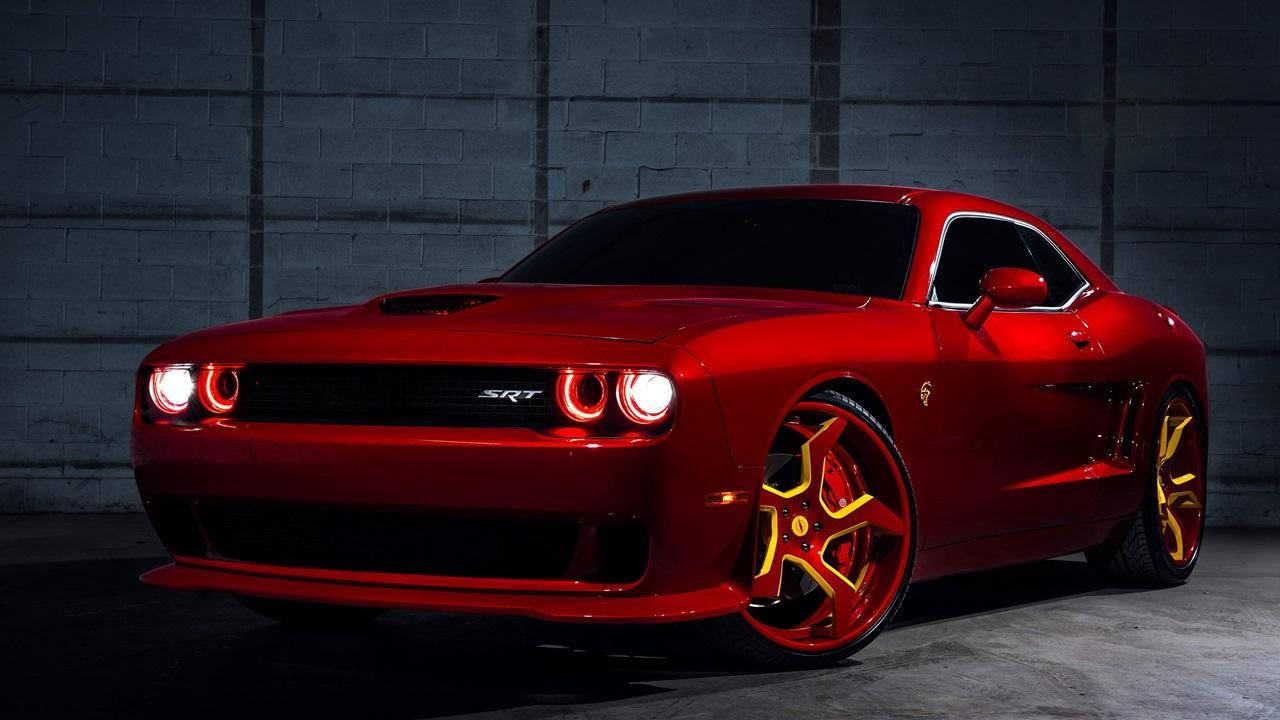 Challenger 桌布 壁紙 — 一輛光澤的紅色Dodge Challenger SRT配金色輪圈，在戲劇性燈光下對著深色混凝土牆發光。