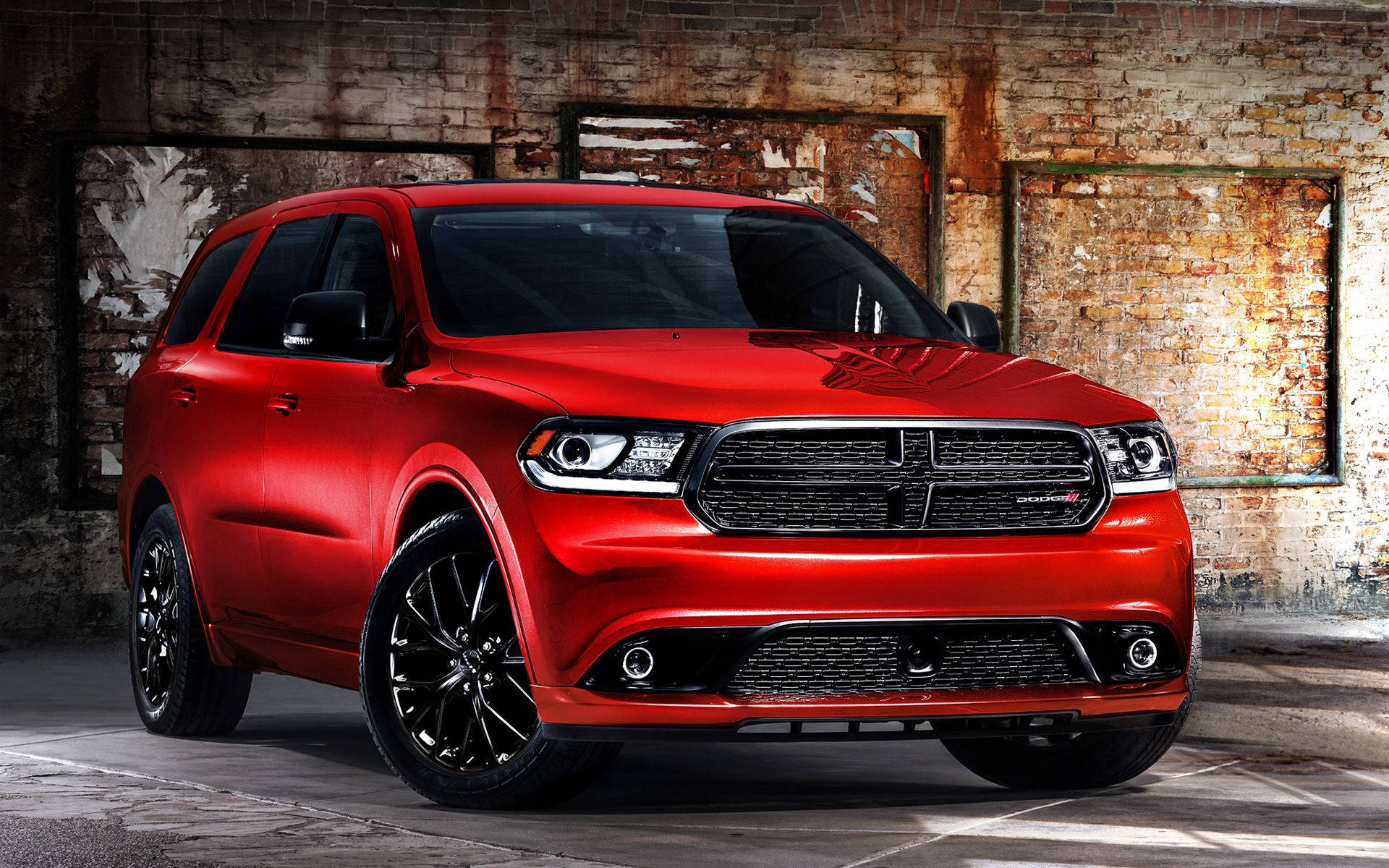 Dodge 桌布 壁紙 — 一輛光澤的紅色Dodge Durango SUV搭配黑色輪圈，大膽地矗立在一個粗糙的工業倉庫中，帶有裸露的磚牆。