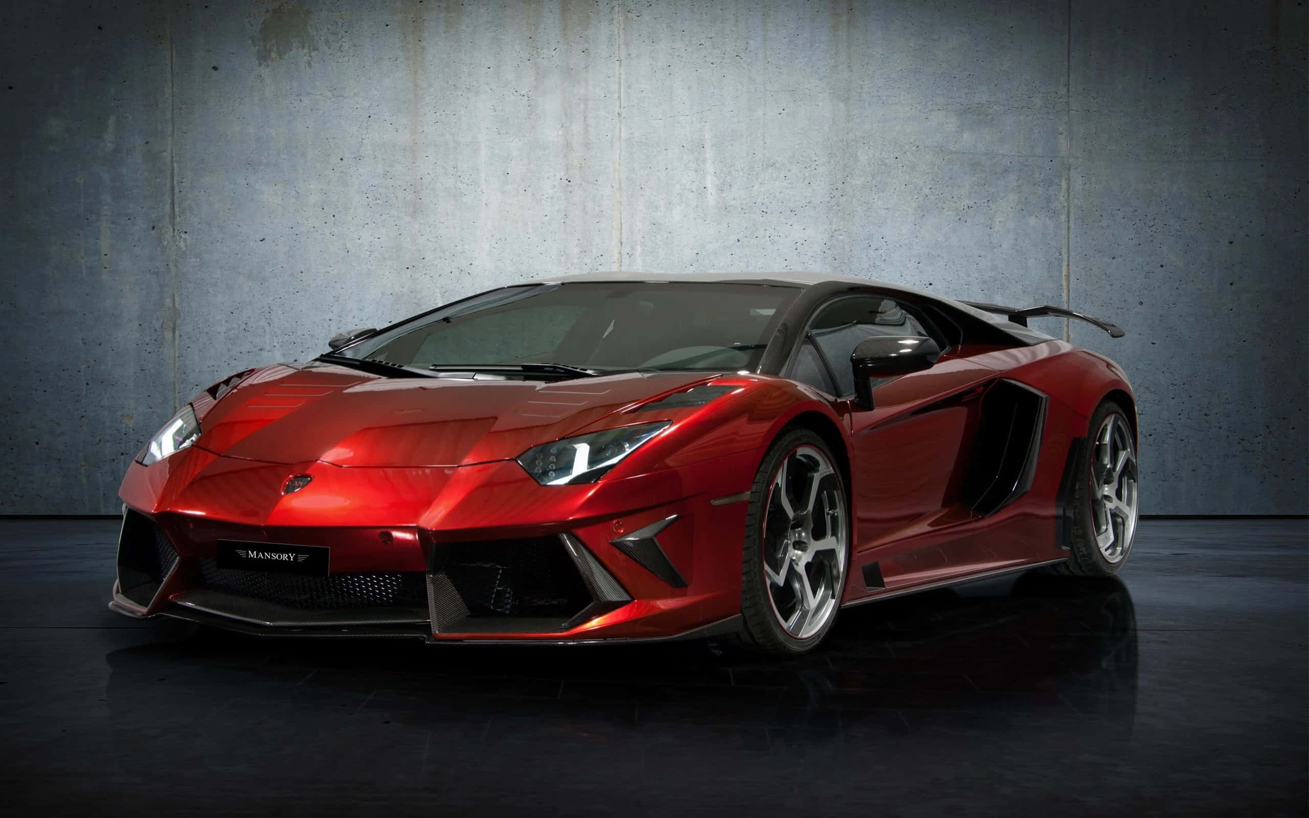 蘭博基尼 桌布 壁紙 — 一輛光澤的紅色Mansory Lamborghini Aventador跑車在攝影棚燈光下，以紋理混凝土牆為背景閃閃發光。