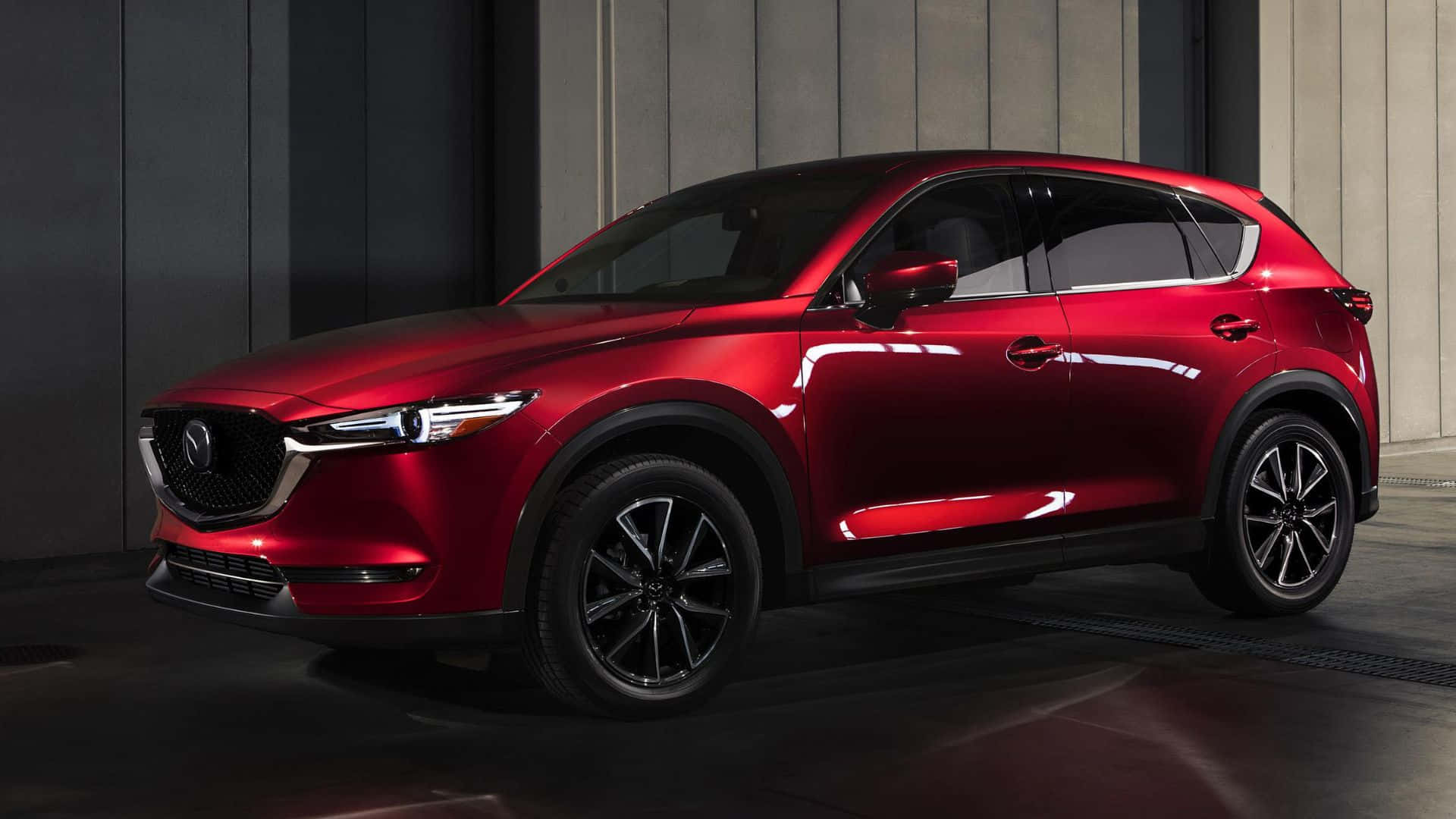 Mazda Cx-5 桌布 壁紙 — 一輛光澤的紅色Mazda CX-5 SUV在現代化的工作室中展示，工作室有深色牆壁和反光地板。