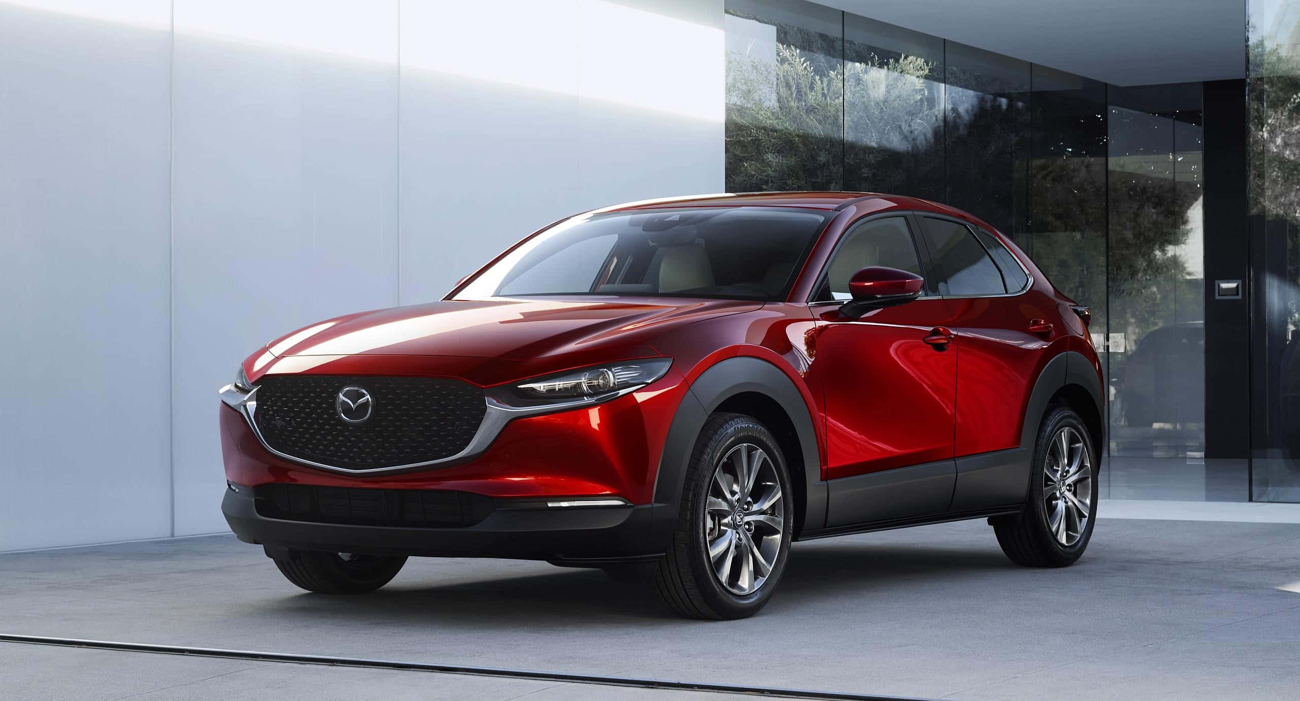 Mazda Cx-30 桌布 壁紙 — 一輛光澤的紅色Mazda CX-30 SUV停在一棟現代玻璃和白色牆壁的建築前。