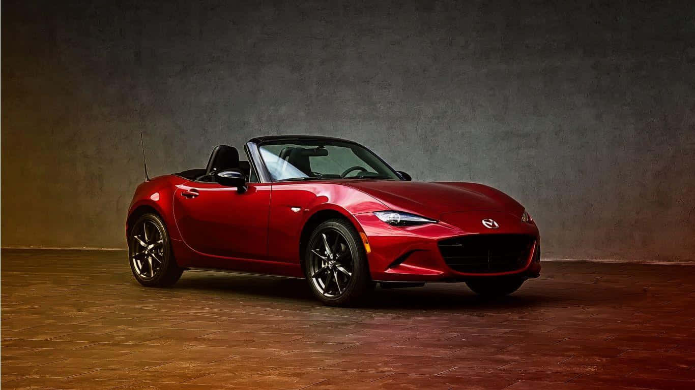 Miata 桌布 壁紙 — 一輛光澤的紅色Mazda MX-5 Miata敞篷車停放在一個有溫暖燈光和紋理牆壁的攝影棚內。