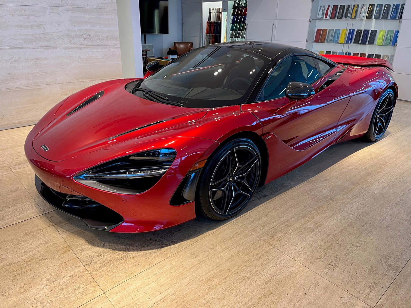 紅色動圖 桌布 壁紙 — 一輛光澤的紅色McLaren 720S超級跑車在展廳燈光下閃耀，停在拋光木地板上。