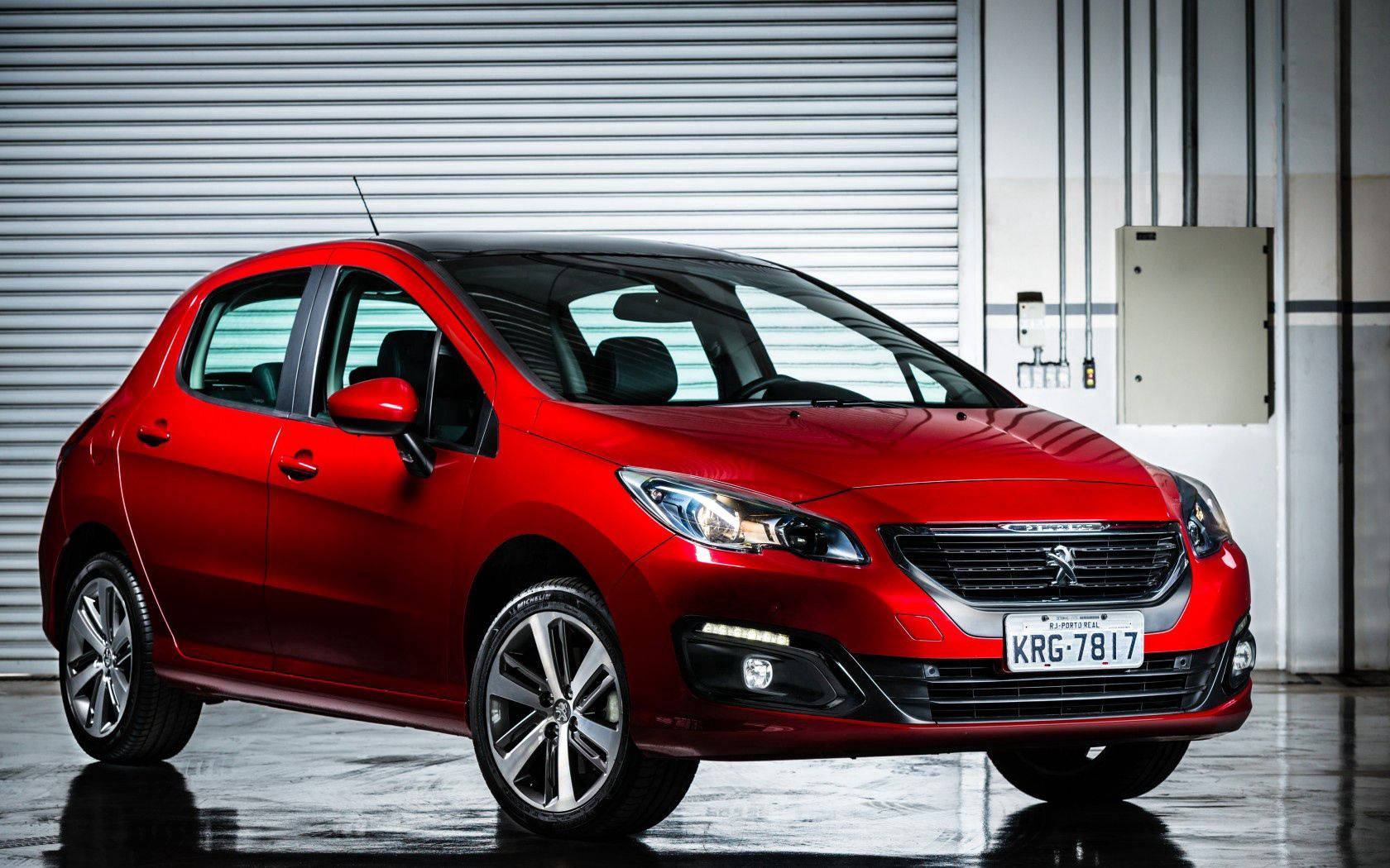 Peugeot 桌布 壁紙 — 一輛光澤的紅色Peugeot 208掀背車在現代工業車庫中，在攝影棚燈光下閃閃發光，地板具有反射效果。