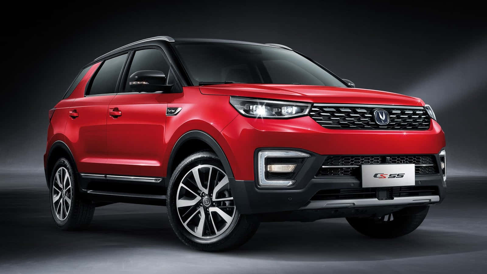 Changan 桌布 壁紙 — 一輛光澤的紅色SUV，帶有黑色飾條和銀色合金輪圈，在深灰色背景下的戲劇性工作室聚光燈中展示。