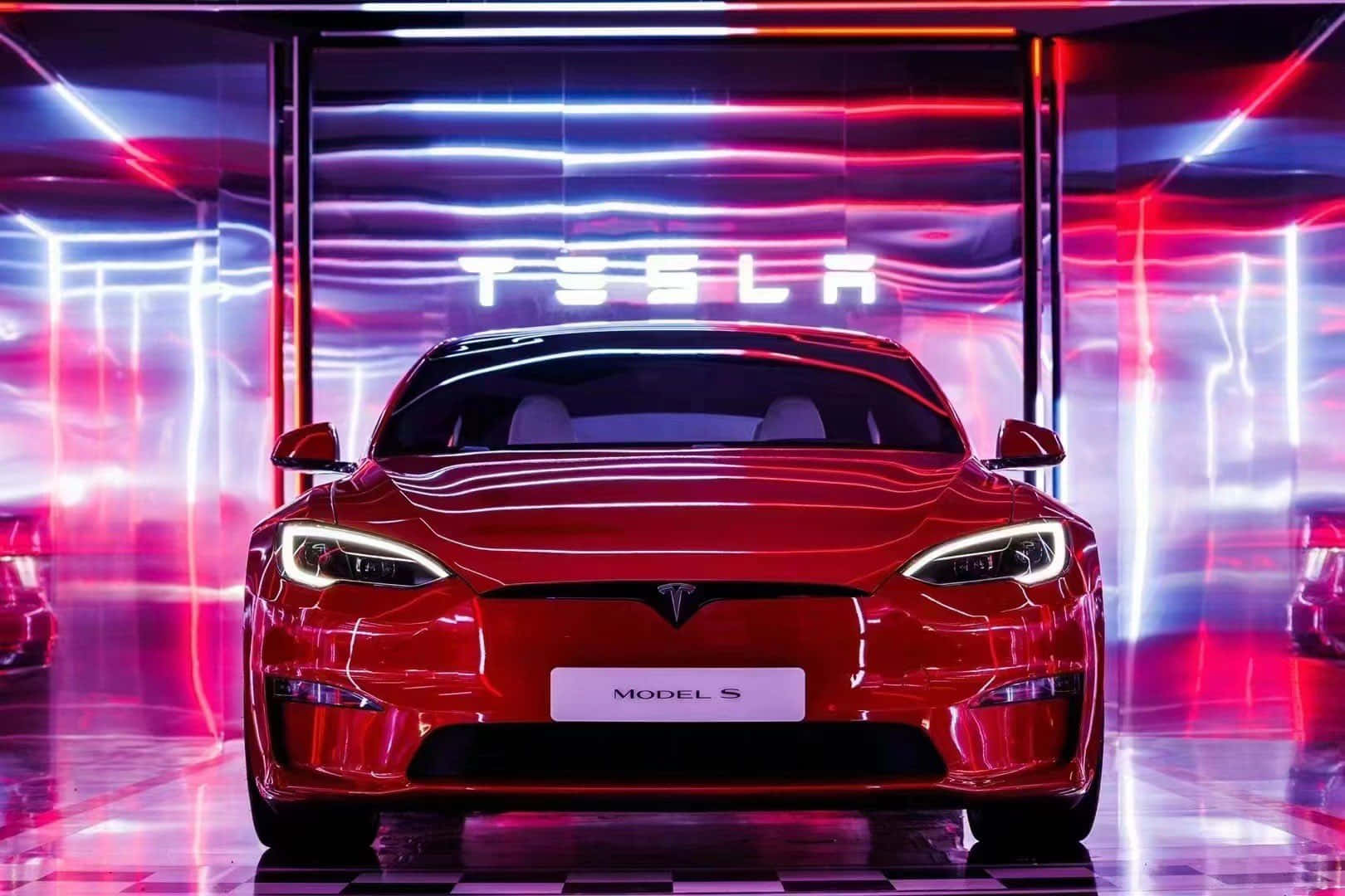 特斯拉 桌布 壁紙 — 一輛光澤的紅色Tesla Model S在充滿活力的霓虹燈下，於帶有棋盤格地板的未來感展廳中正面朝前。