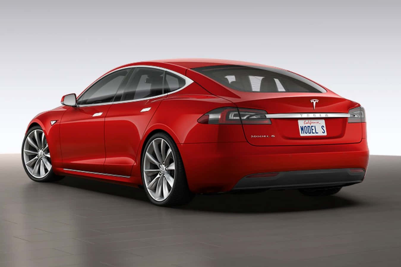 特斯拉 桌布 壁紙 — 一輛光澤的紅色Tesla Model S轎車以四分之三後視圖顯示，背景為簡約的工作室背景。