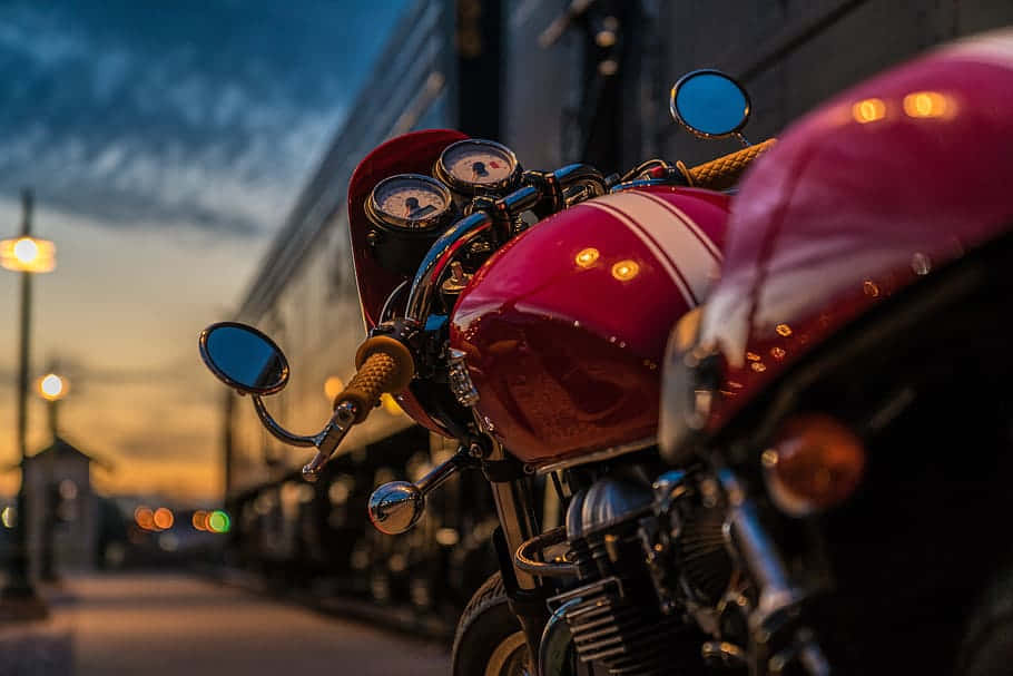  壁紙 — 一輛光澤的紅色復古摩托車在暮色街燈下閃耀，背景有散景燈光。