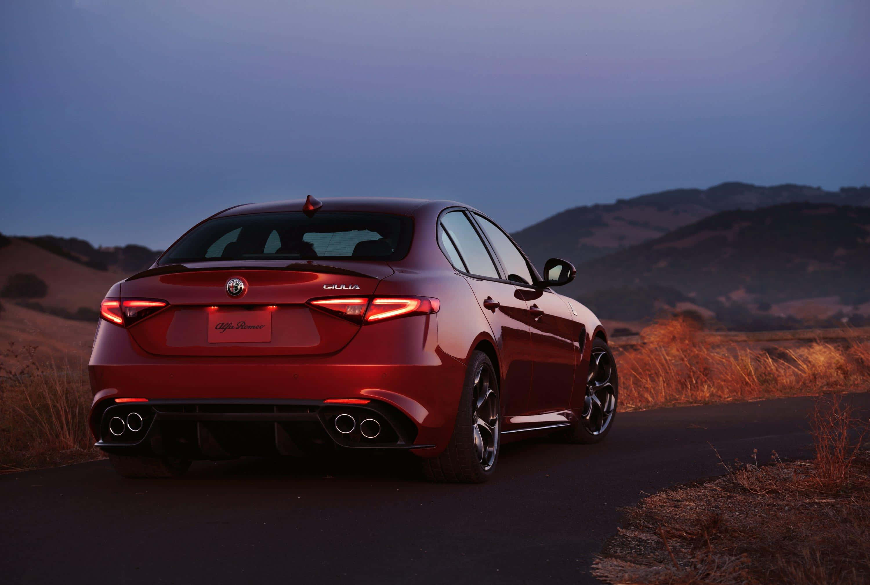 Alfa Romeo Giulia 桌布 壁紙 — 一輛光澤的紅色愛快羅密歐Giulia轎車在黃昏時分在蜿蜒的道路上閃耀，背景是山丘。