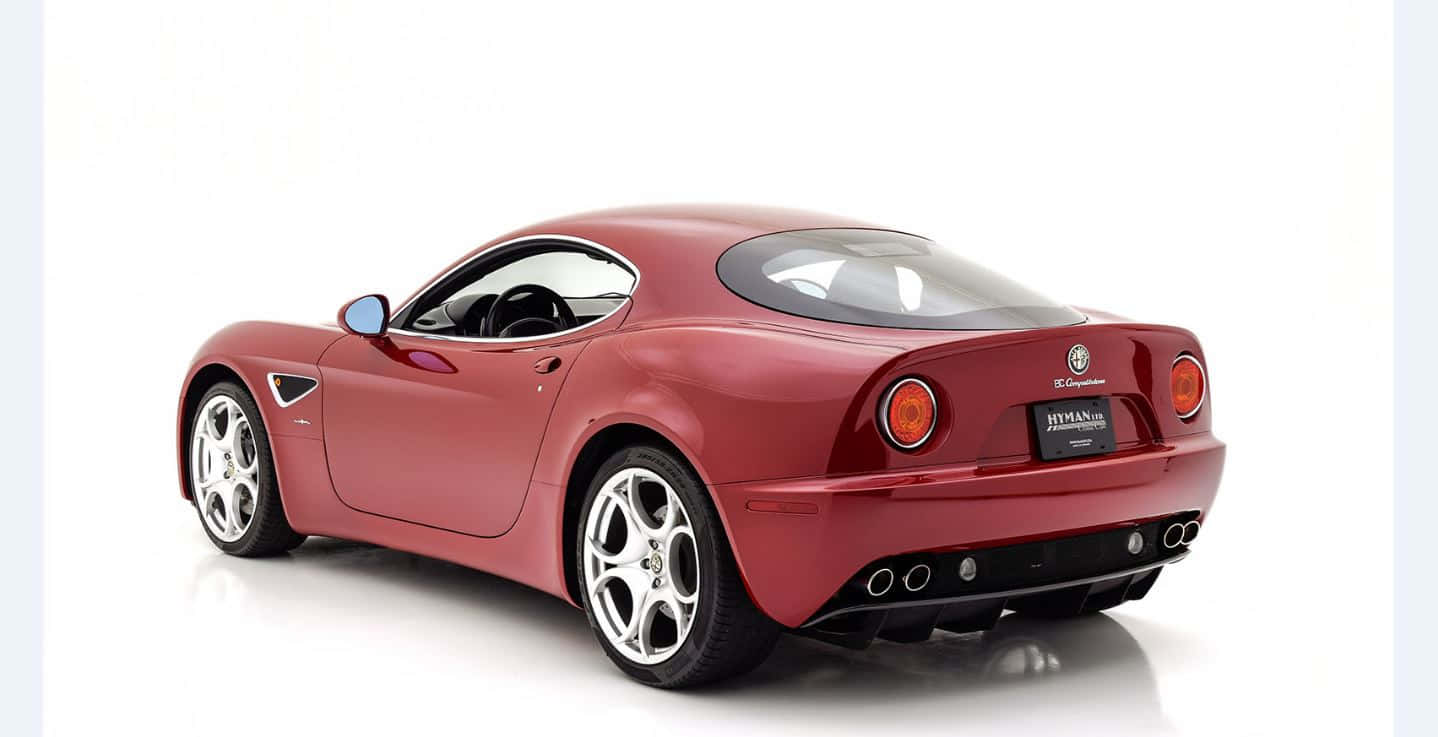 Alfa Romeo 8c Competizione 桌布 壁紙 — 一輛光澤的紅色愛快羅密歐跑車在工作室燈光下展示，背景為純白色，地板有反射效果。
