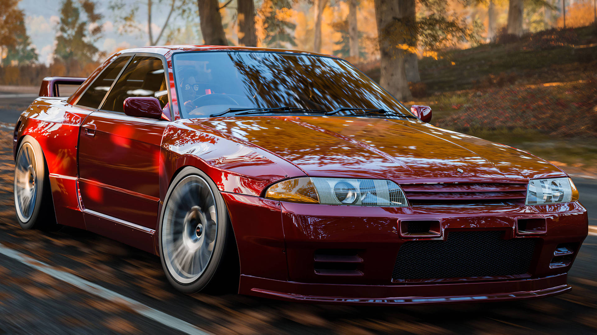 電玩遊戲 桌布 壁紙 — 一輛光澤的紅色日產Skyline R34在陽光明媚的秋日森林中飄移，金色樹葉在車輪周圍旋轉。