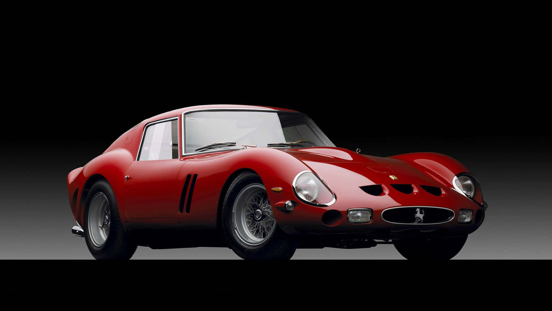 Vintage Ferrari 桌布 壁紙 — 一輛光澤的紅色法拉利250 GTO跑車，帶有黑色賽車條紋和銀色鋼絲輪，在黑色和灰色漸變的攝影棚背景前蓄勢待發。