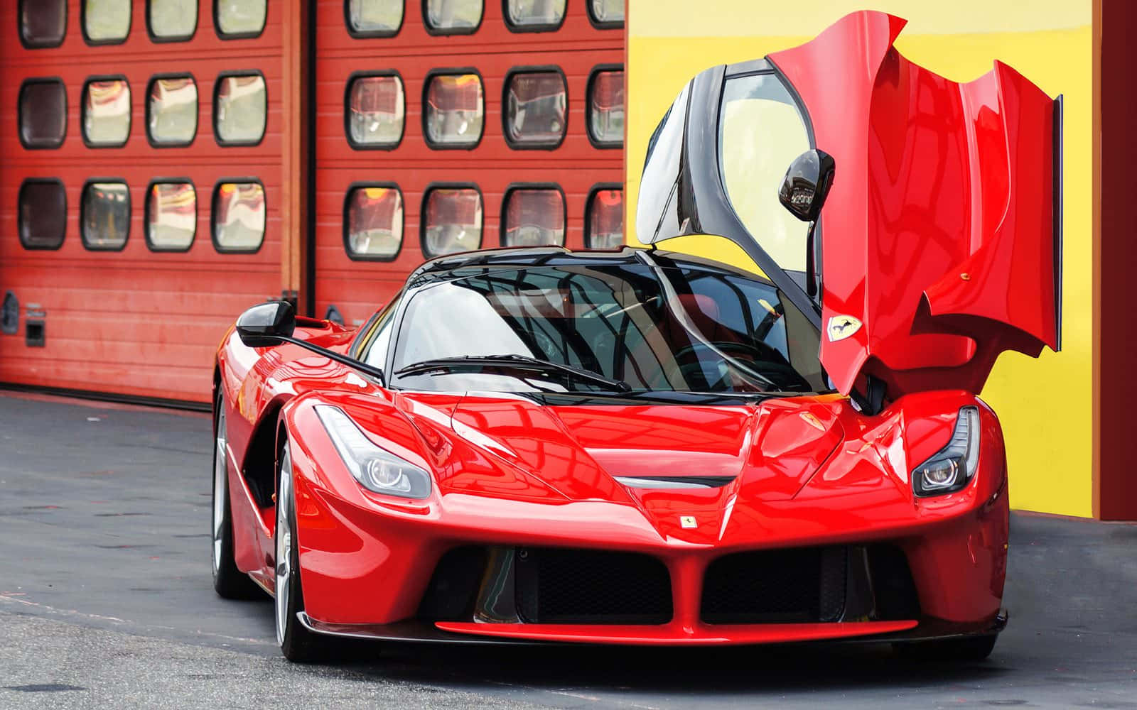 Ferrari Laferrari 桌布 壁紙 — 一輛光澤的紅色法拉利LaFerrari跑車，其鷗翼門打開，停在紅色和黃色的車庫門前。