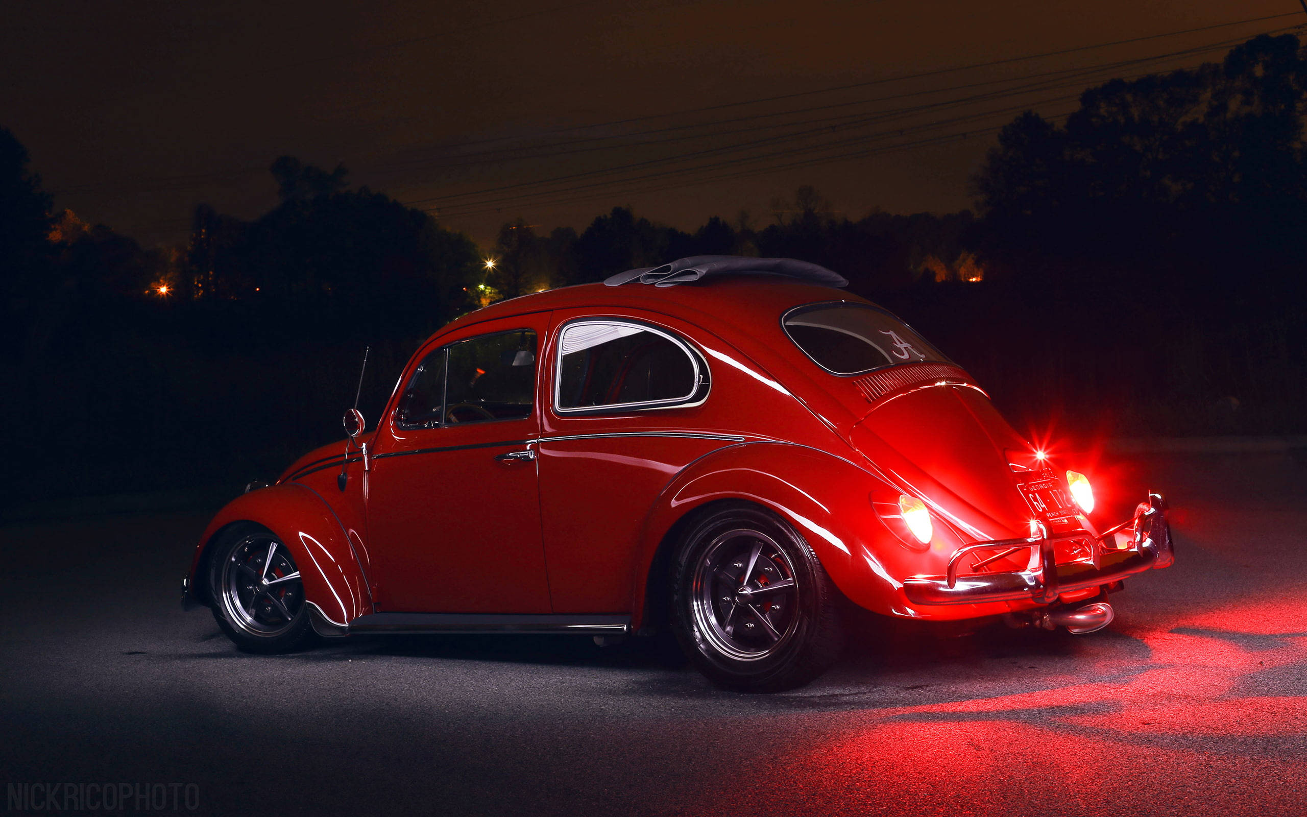 Lowrider 桌布 壁紙 — 一輛光澤的紅色經典福斯金龜車在黑暗的夜間道路上，在自己的尾燈下發光。