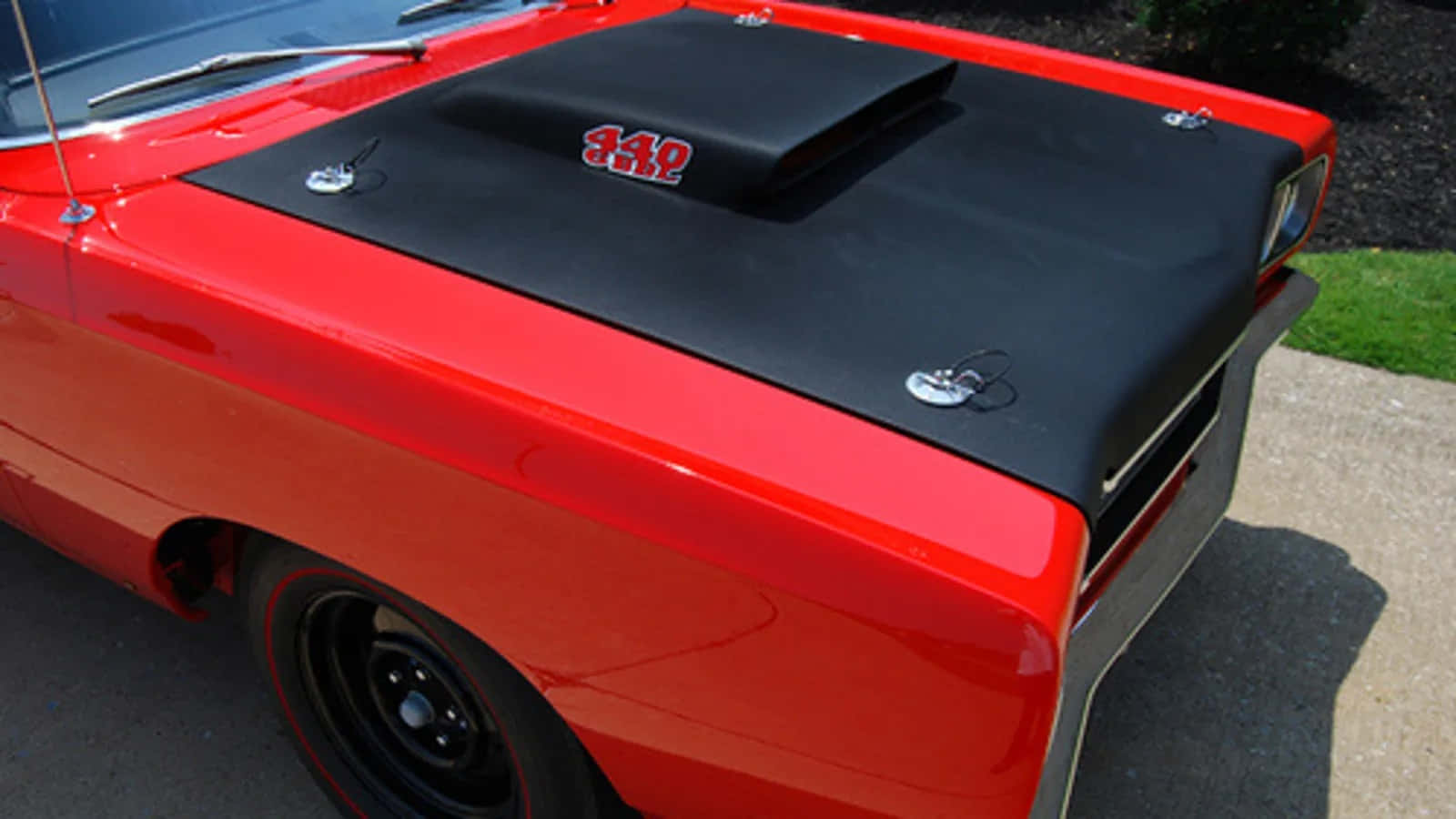 Car Hood 桌布 壁紙 — 一輛光澤的紅色經典肌肉車，帶有黑色引擎蓋進氣口和 '340' 標誌，停在陽光明媚的車道上。