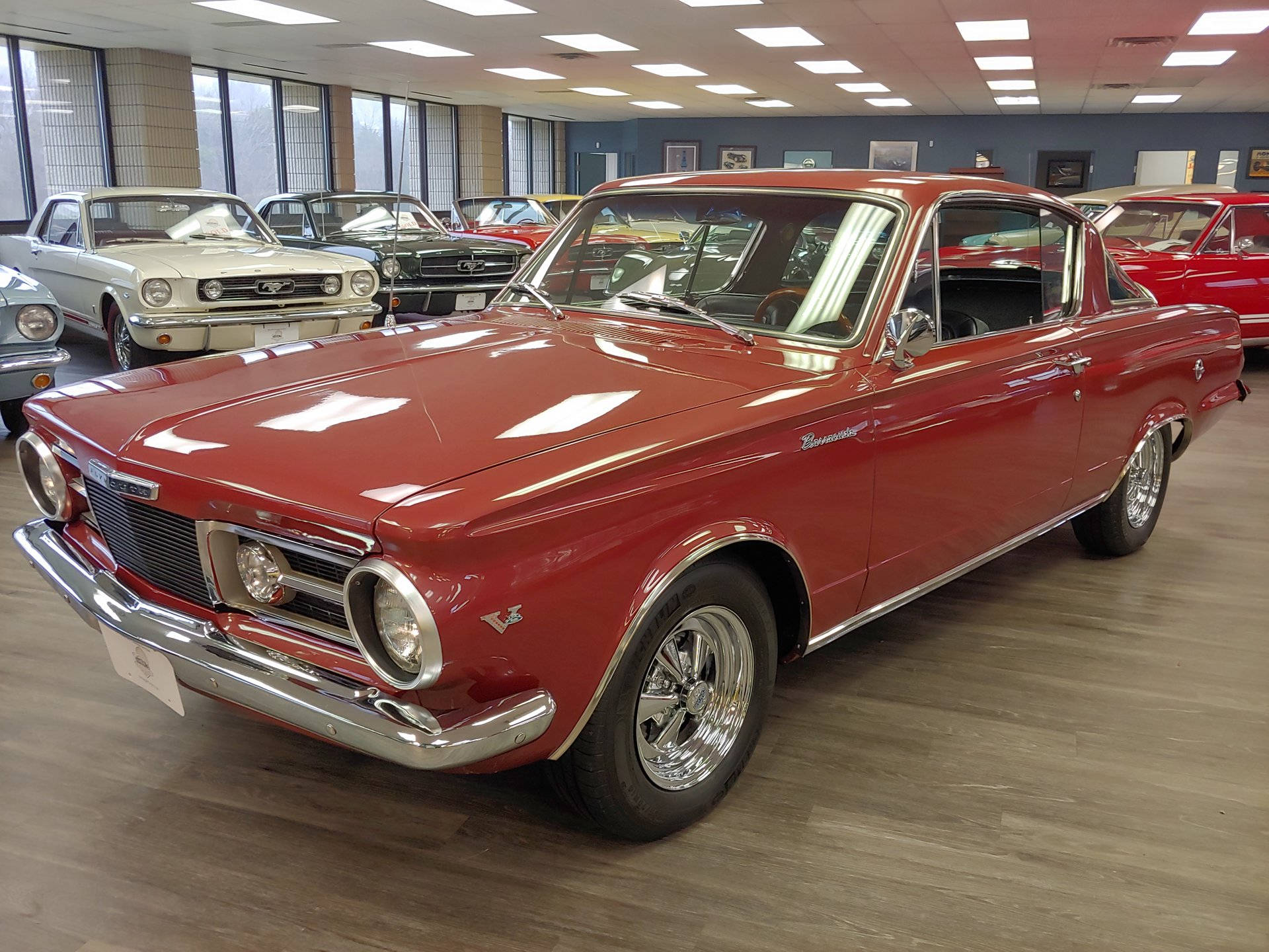 Barracuda 桌布 壁紙 — 一輛光澤的紅色經典肌肉車在展廳燈光下閃耀，配備鍍鉻裝飾和白色側壁輪胎。