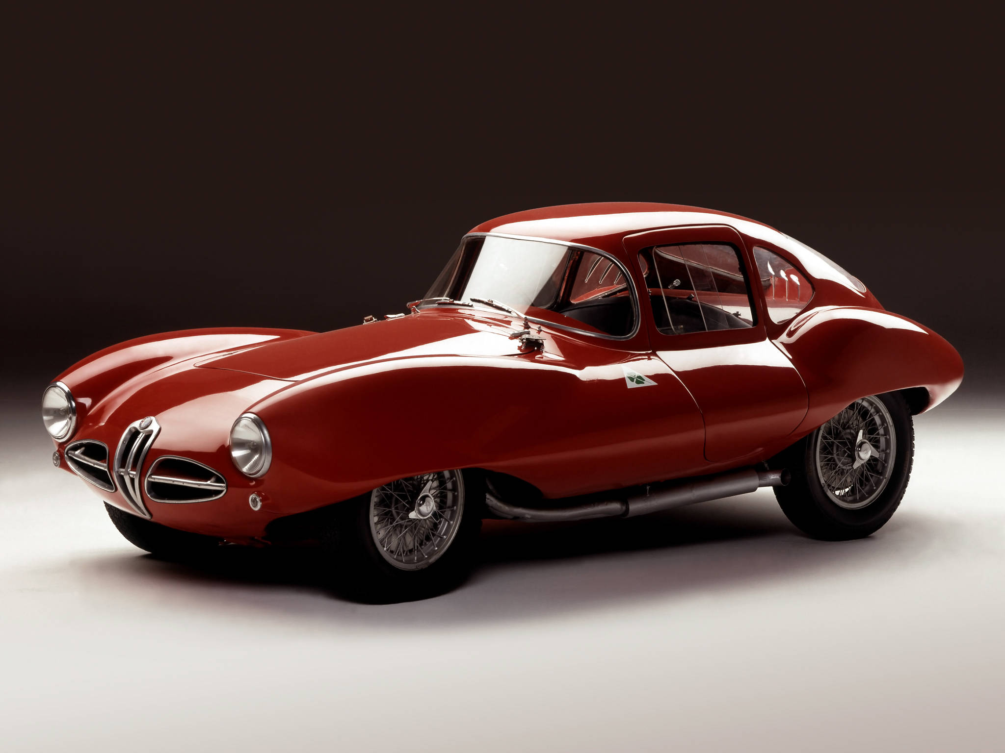 alfa romeo iPhone 桌布 壁紙 — 一輛光澤的紅色經典阿爾法羅密歐跑車，配有鋼絲輪圈和鍍鉻裝飾，在深色工作室背景下擺拍。