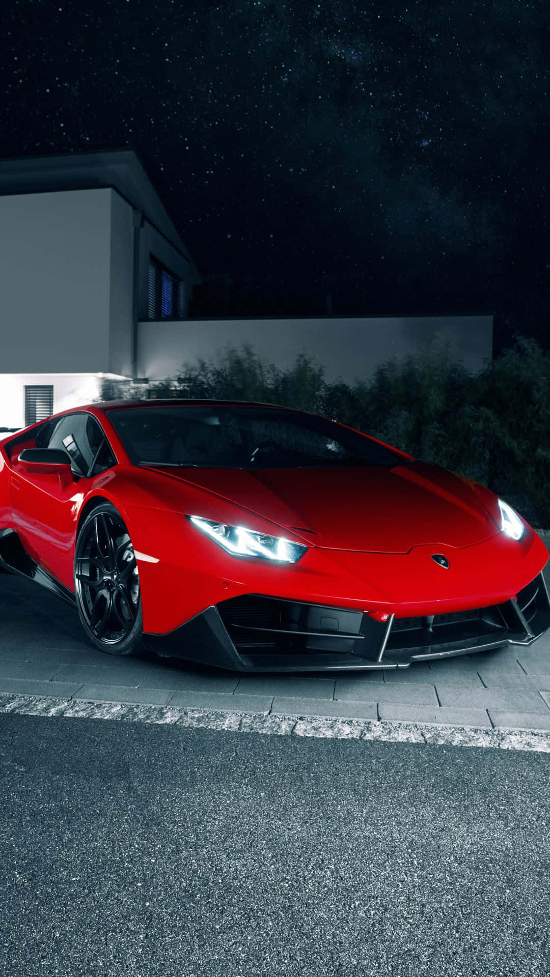 Pixel 3xl Lamborghini 桌布 壁紙 — 一輛光澤的紅色藍寶堅尼Huracán停放在鋪砌的車道上，背景是星空下的現代房屋。