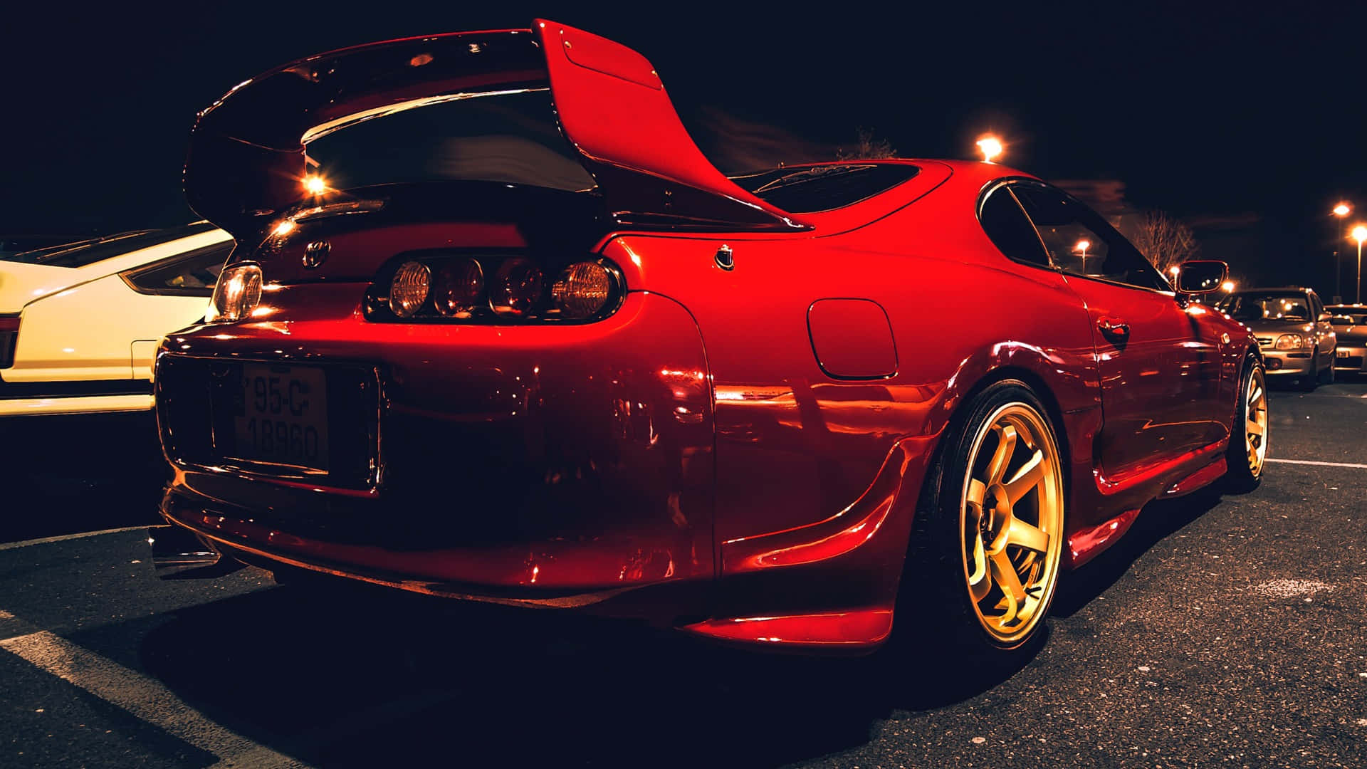 紅色定制跑車配備金色輪圈，夜晚停在有照明的停車場。 — Toyota Supra Mk4 壁紙
