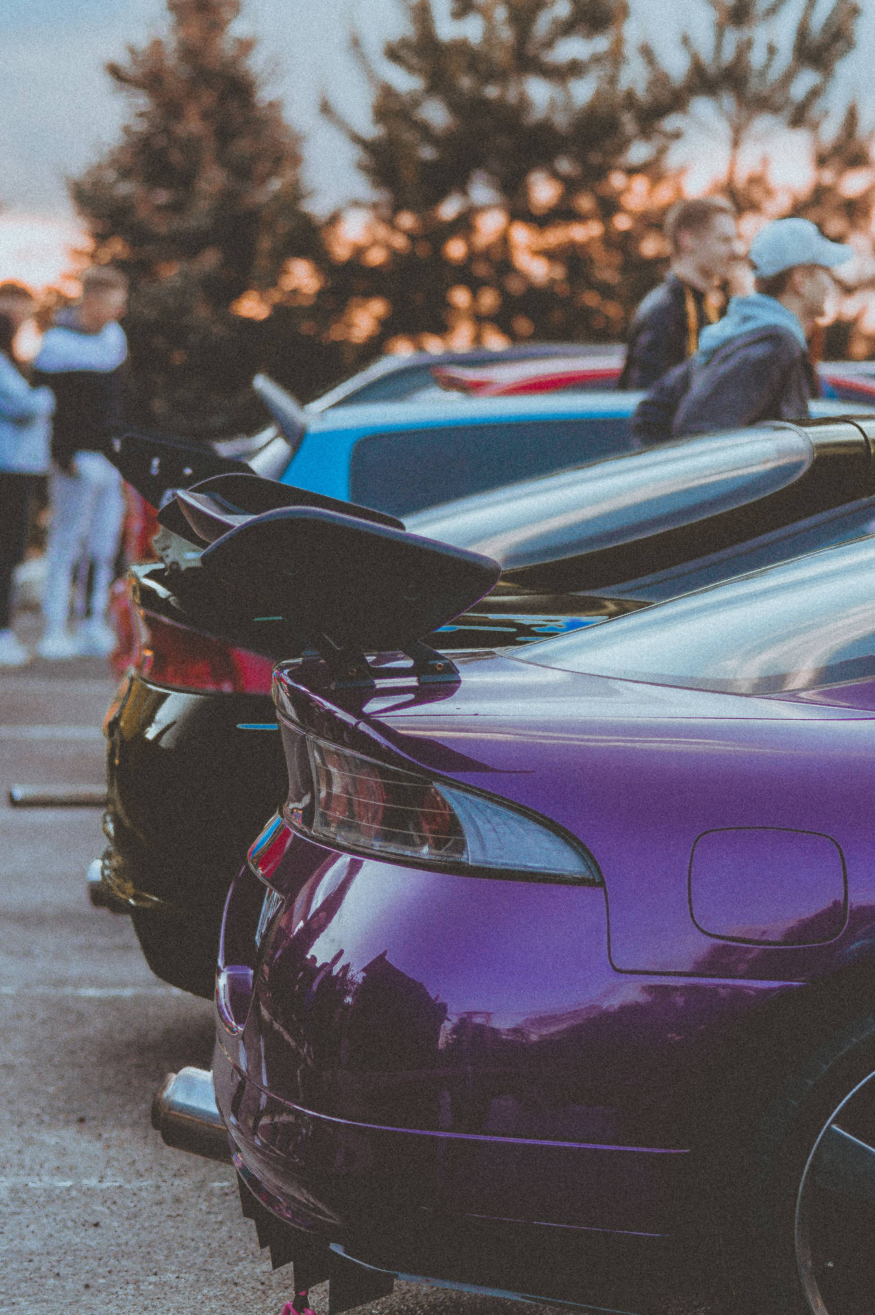 紫色跑車帶擾流板停在日落時分的人們附近。 — 4K Jdm 壁紙