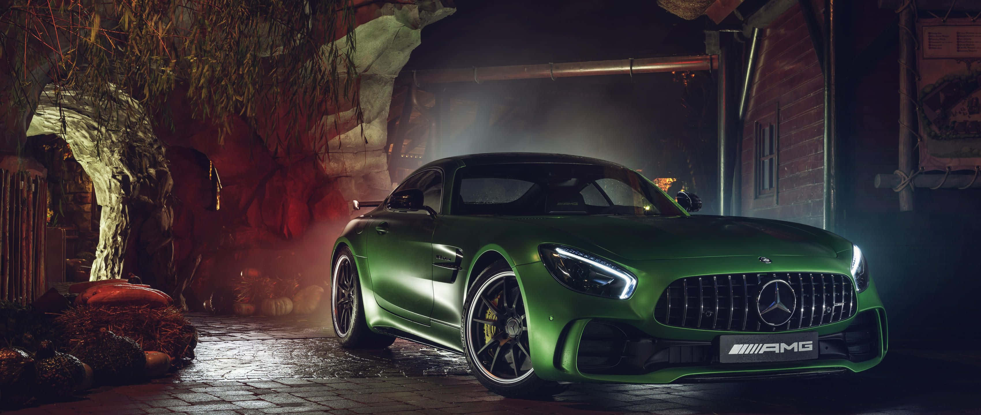 Mercedes 桌布 壁紙 — 一輛光澤的綠色 Mercedes-AMG GT 停放在光線昏暗的鄉村風格車庫中，帶有戲劇性的燈光和薄霧。