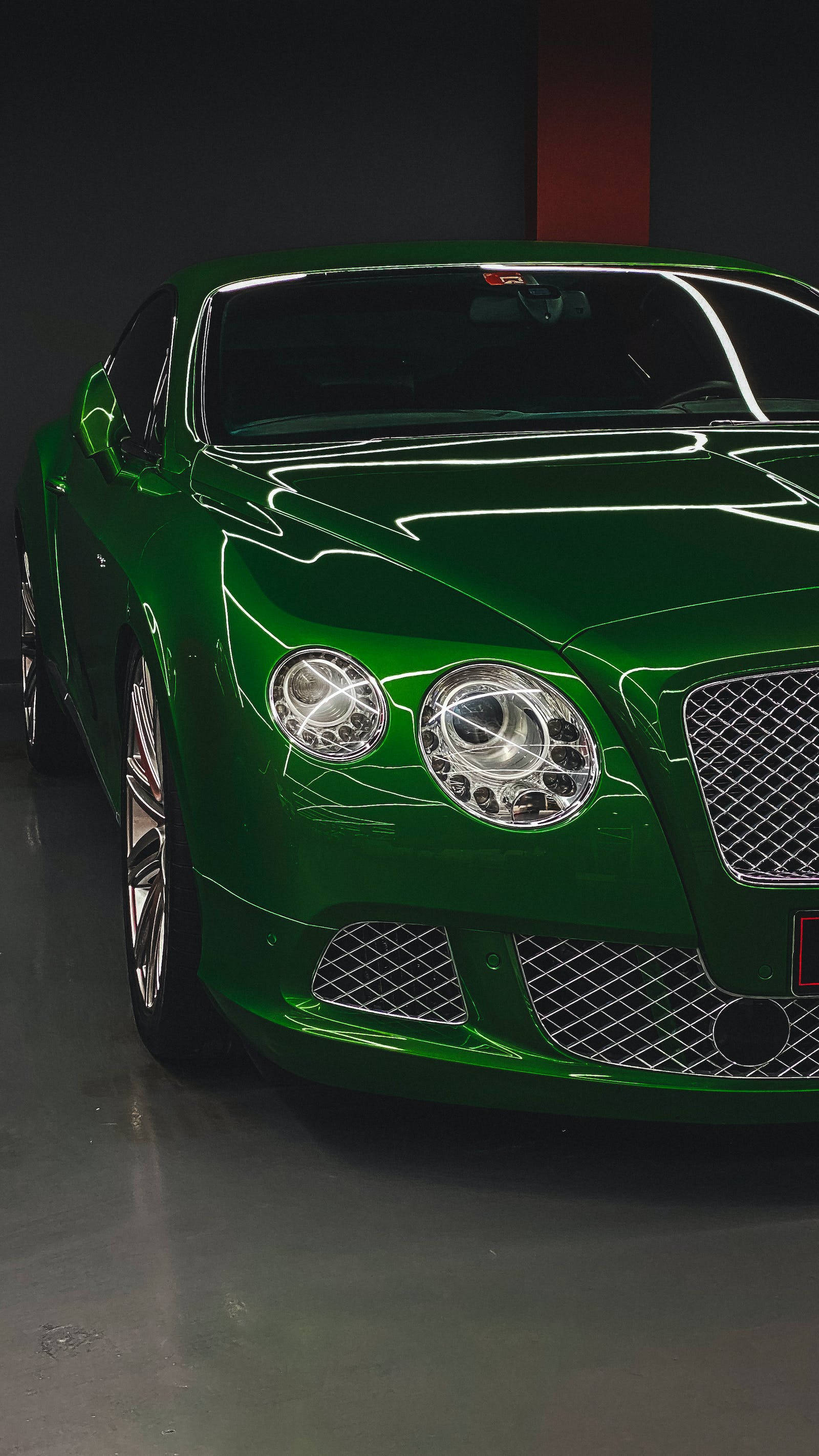 bentley HD 桌布 壁紙 — 一輛光澤的翡翠綠色賓利 Continental GT 在極簡的黑暗車庫中於攝影棚燈光下閃耀。