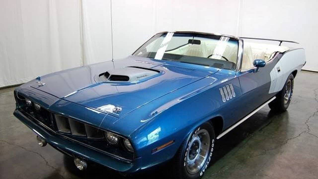 Barracuda 桌布 壁紙 — 一輛光澤的藍色經典敞篷肌肉車，帶有白色條紋和鍍鉻細節，停在室內混凝土地板上。
