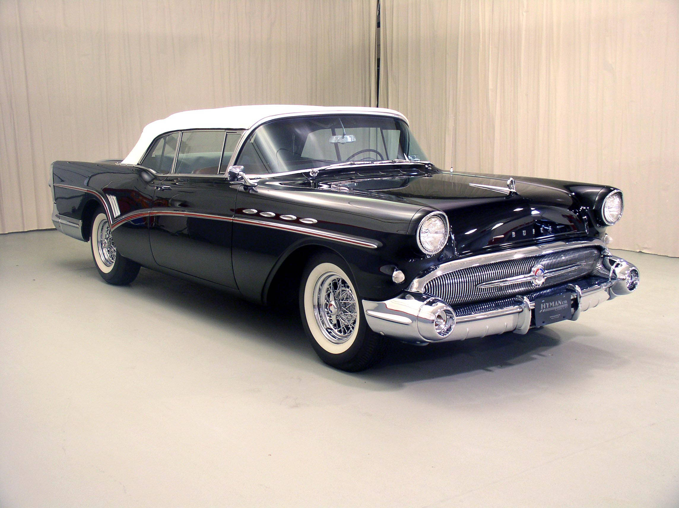 Buick 桌布 壁紙 — 一輛光澤的黑色1950年代別克路霸敞篷車，白色車頂和鍍鉻裝飾在攝影棚燈光下閃閃發光。