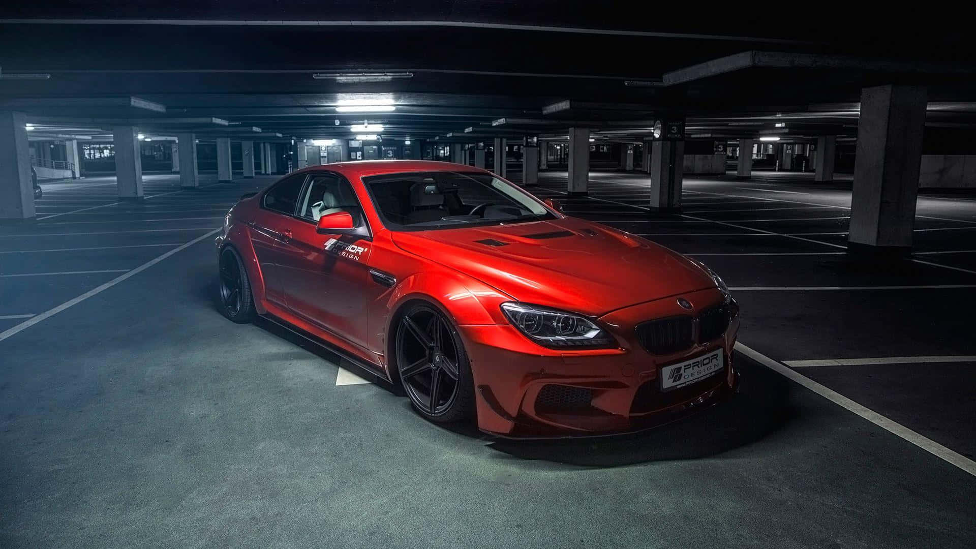 Bmw 6 Series 桌布 壁紙 — 一輛光澤紅色BMW M6跑車獨自停放在燈光昏暗、天花板燈光刺眼的地下停車場。