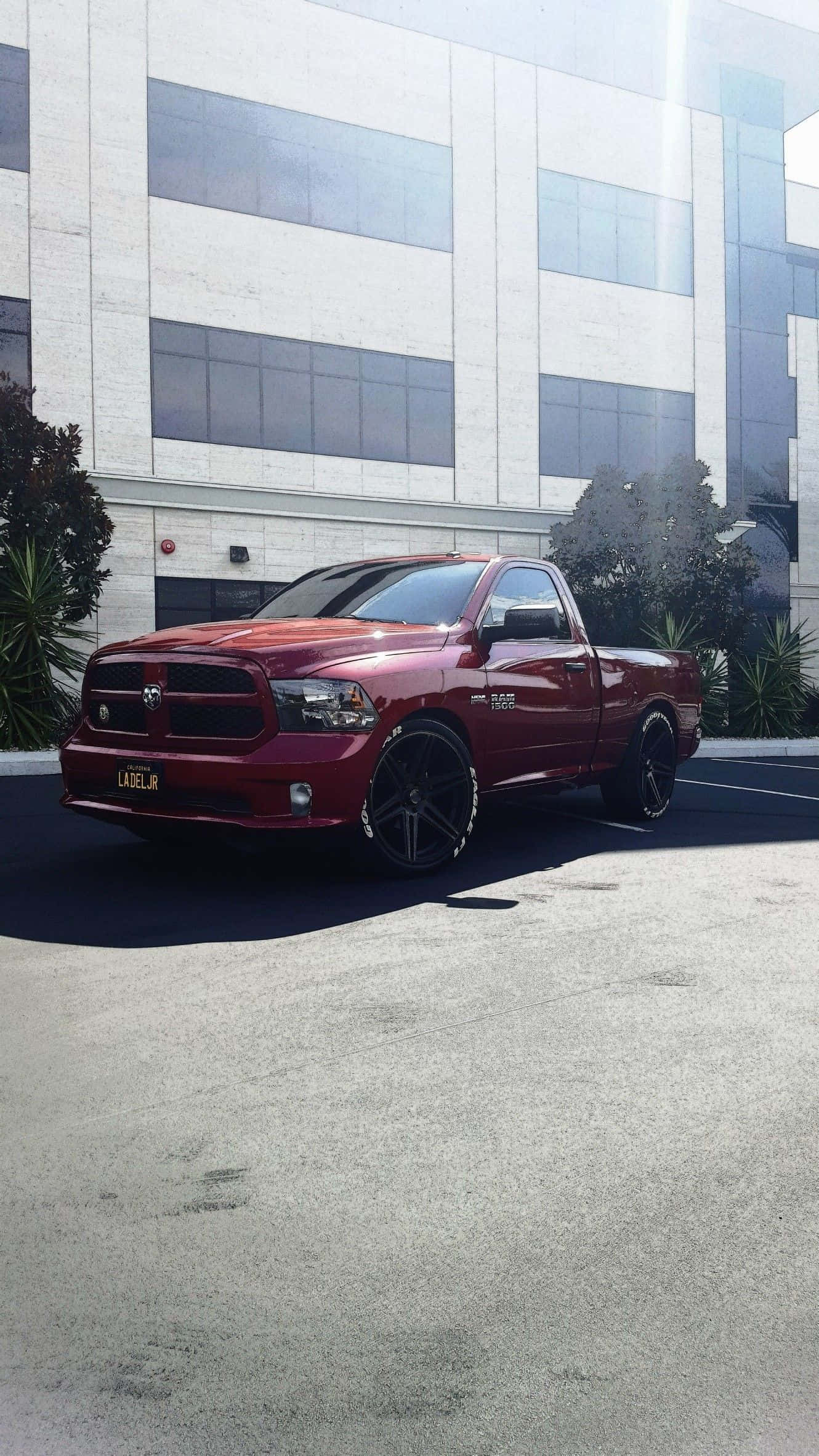 Trucks 桌布 壁紙 — 一輛光澤紅色Ram皮卡車配黑色輪圈，停在一棟現代玻璃和混凝土建築前。