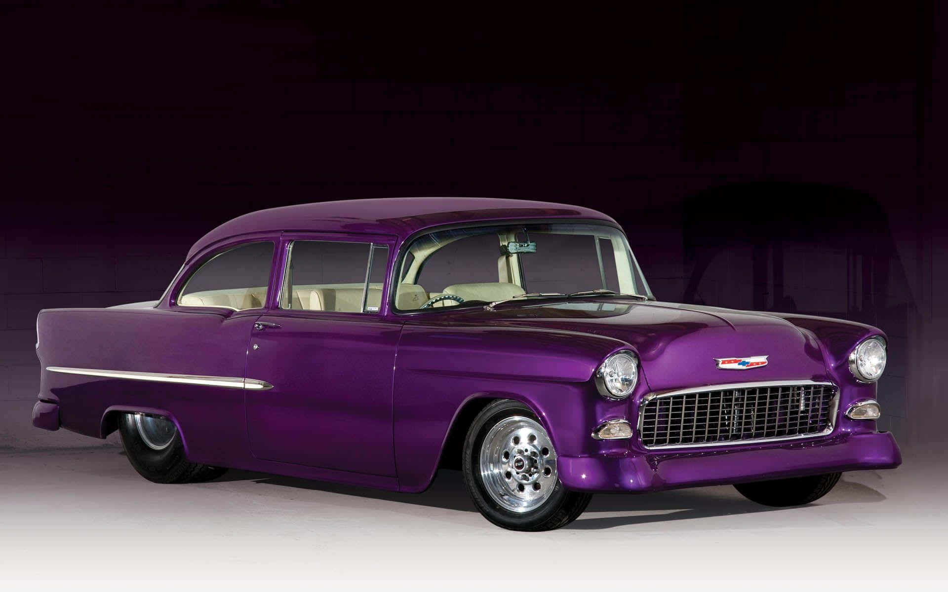 chevy 桌布 壁紙 — 一輛光澤紫色1950年代雪佛蘭，帶有鍍鉻裝飾和奶油色內飾，在深色漸變工作室背景中展示。