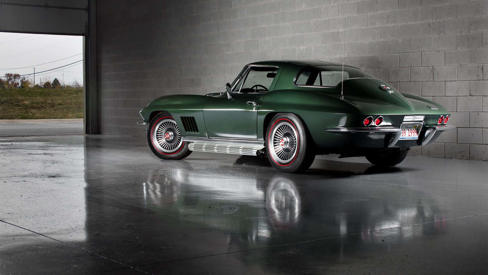 classic 桌布 壁紙 — 一輛光澤綠色經典Corvette跑車停放在混凝土車庫內，其倒影在濕滑的地板上閃爍。